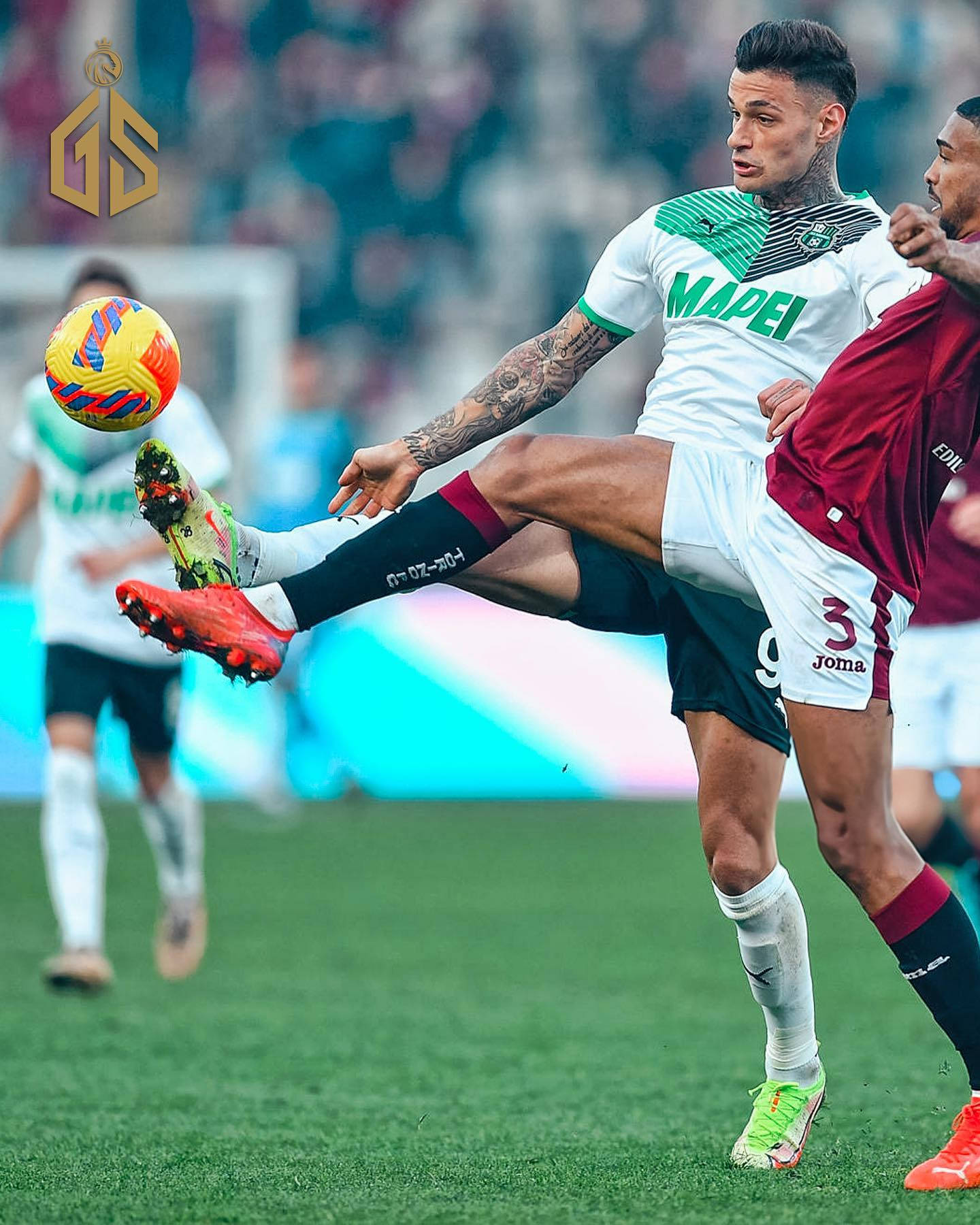 West Ham United Fc 桌布 壁紙 — 一名身穿白色球衣的足球員在球場比賽中凌空踢出一個充滿活力的足球，而一名身穿紅色球衣的對手正在防守。