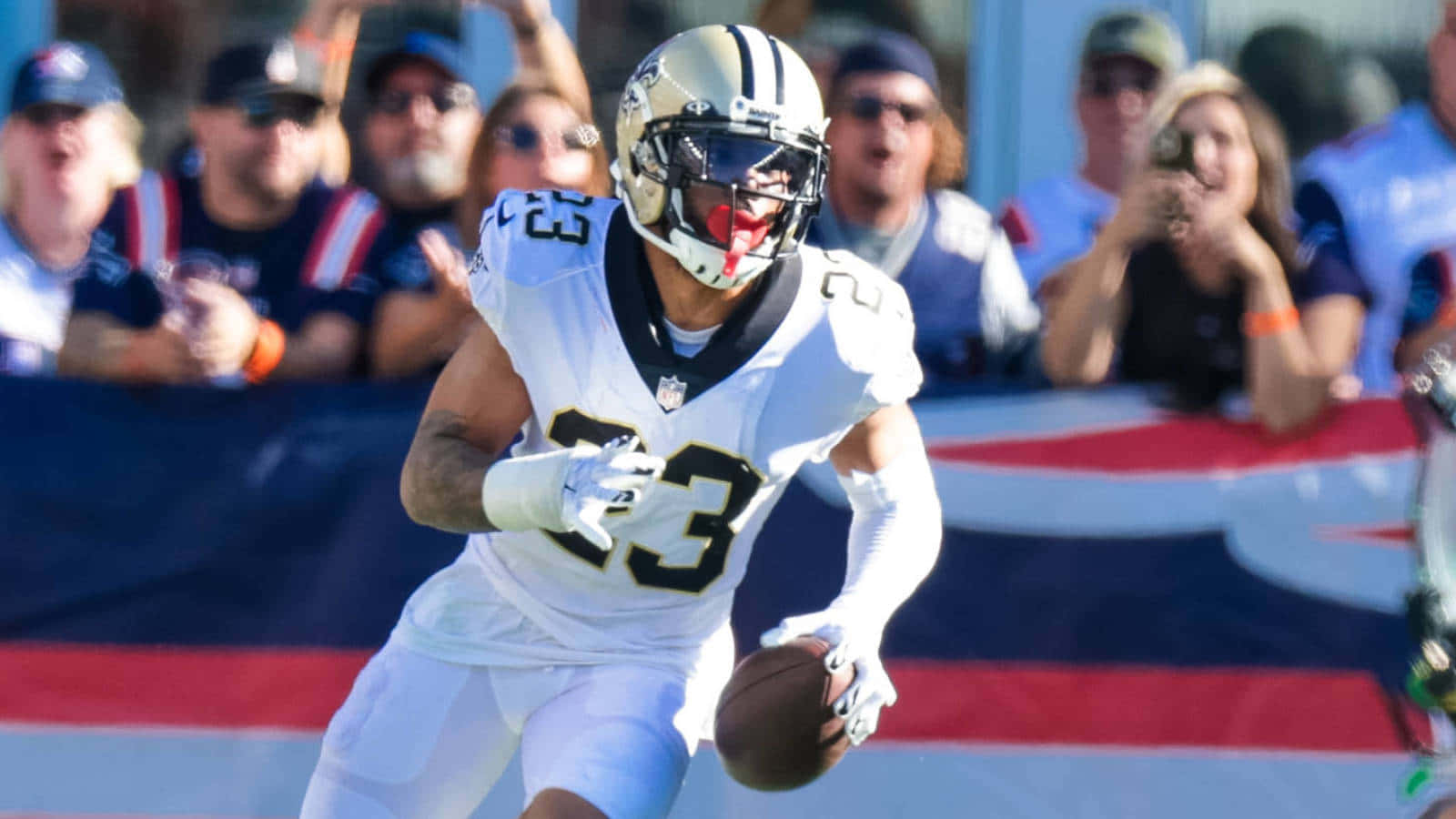 New Orleans Saints 桌布 壁紙 — 一名身穿白色球衣的足球員帶球衝刺，背景有球迷歡呼。