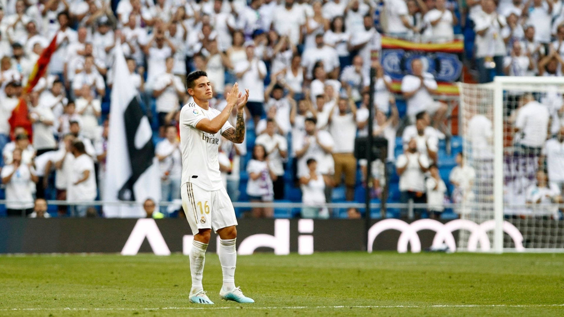 James Rodriguez 桌布 壁紙 — 一名身穿白色球衣的足球運動員在明亮的日光下，於座無虛席的體育場向球迷鼓掌致意。