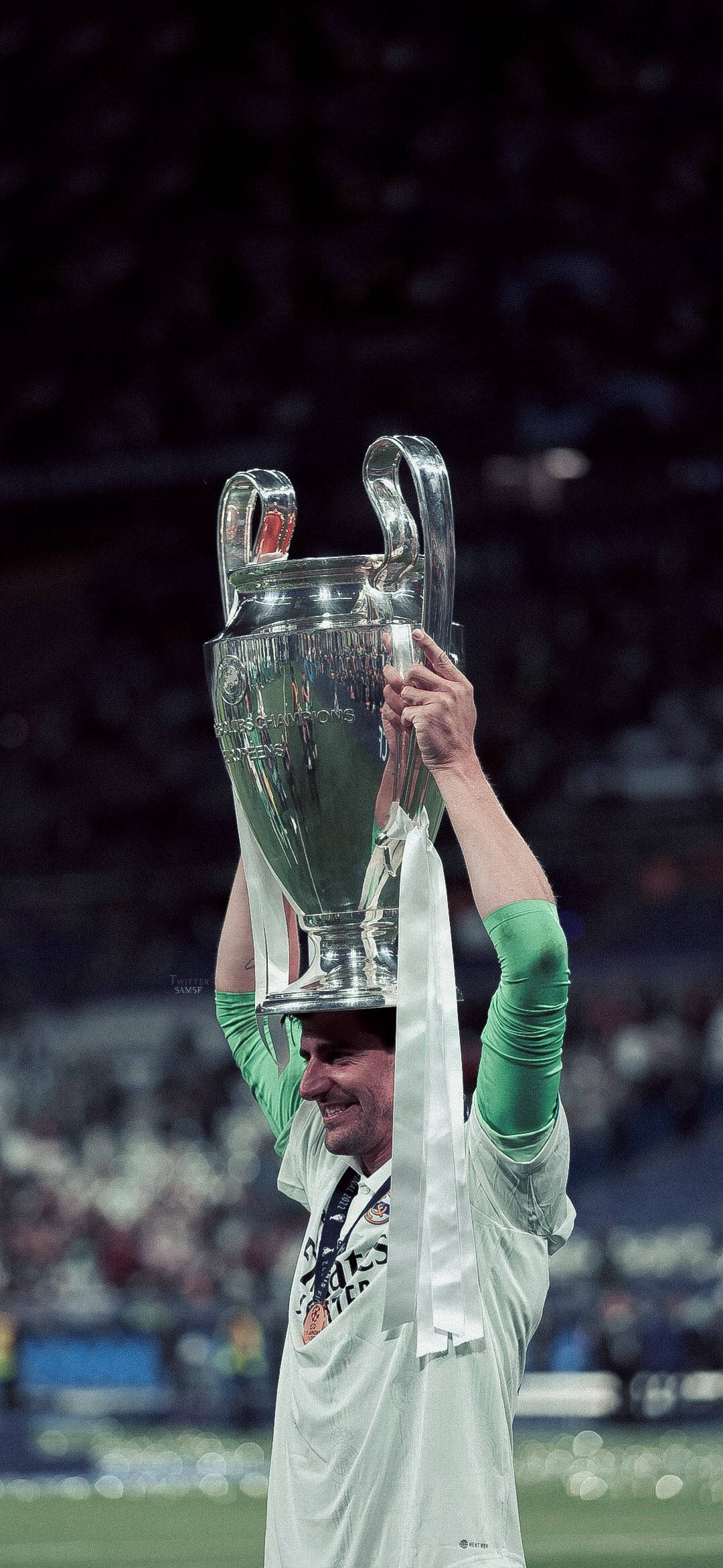 Champions League 桌布 壁紙 — 一名身穿白色球衣的足球運動員在球場上勝利地將閃亮的銀色歐洲聯賽冠軍盃高舉過頭頂。
