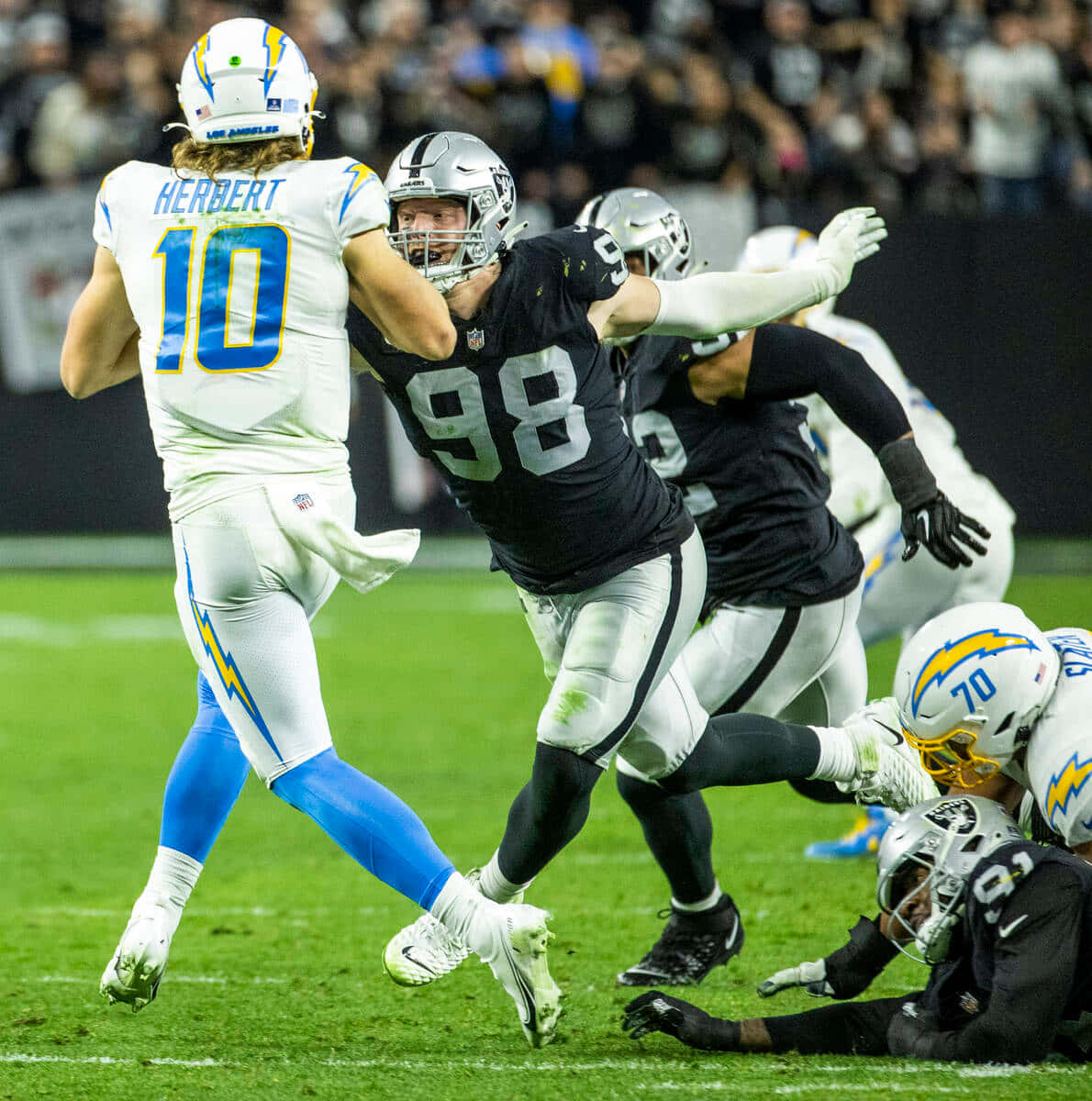 Football Players 桌布 壁紙 — 一名身穿白色的美式足球四分衛在夜間比賽中被一名身穿黑色的防守球員擒抱。