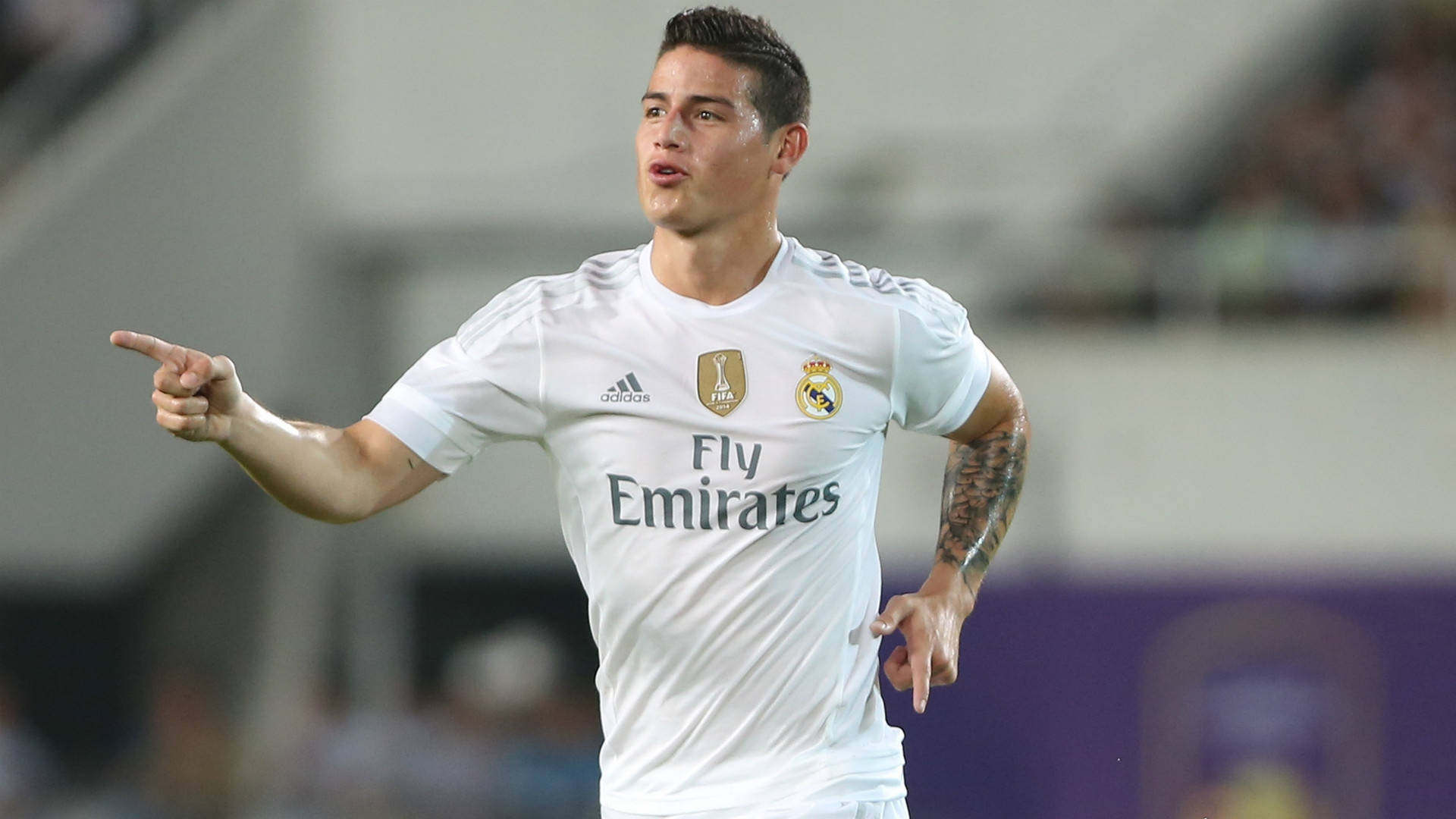 James Rodriguez 桌布 壁紙 — 一名身穿白色皇家馬德里球衣的足球員在球場燈光下自信地指著。