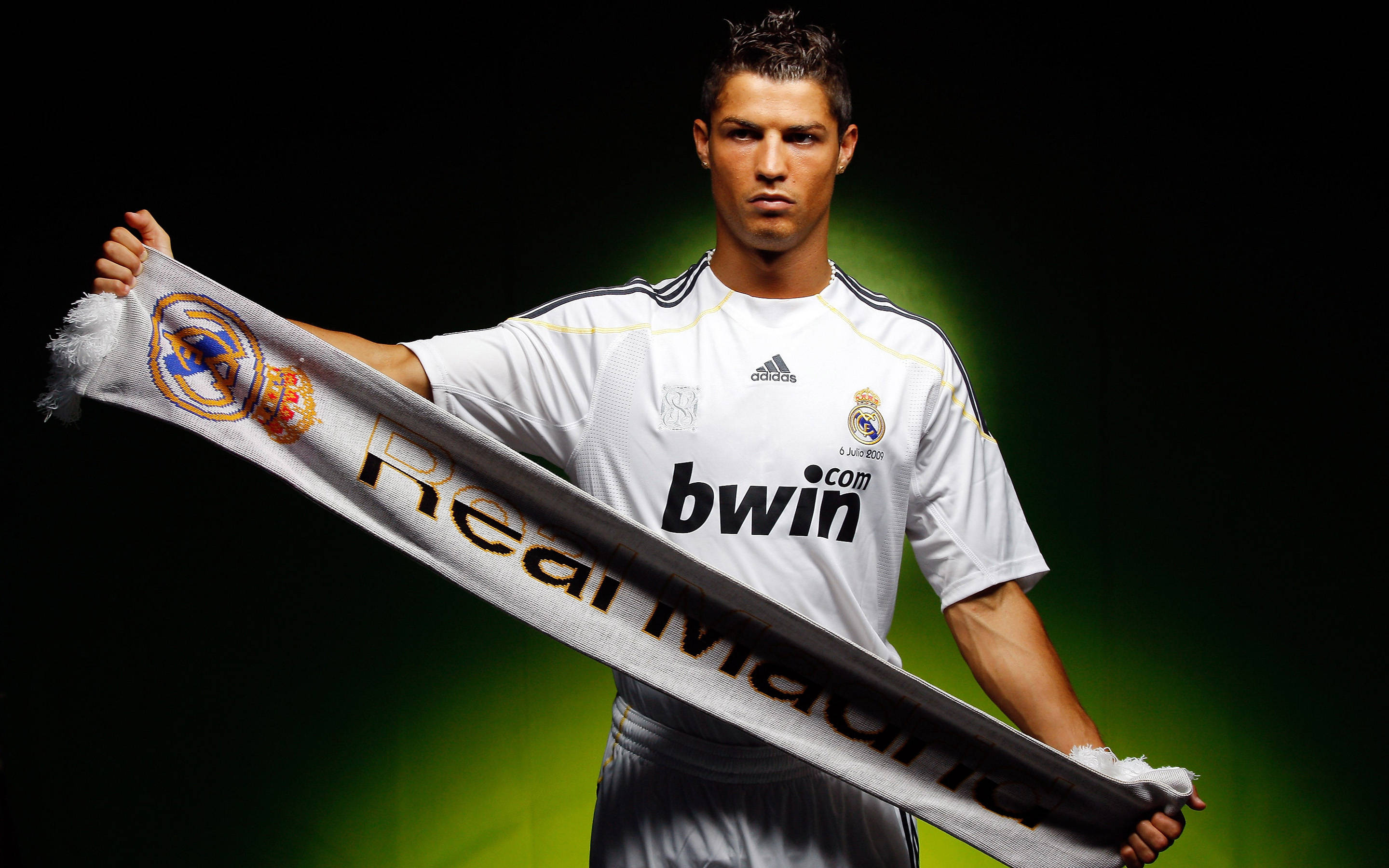 Cr7 桌布 壁紙 — 一名身穿白色皇家馬德里球衣的足球員，在帶有綠色燈光的深色背景前舉起球隊圍巾。