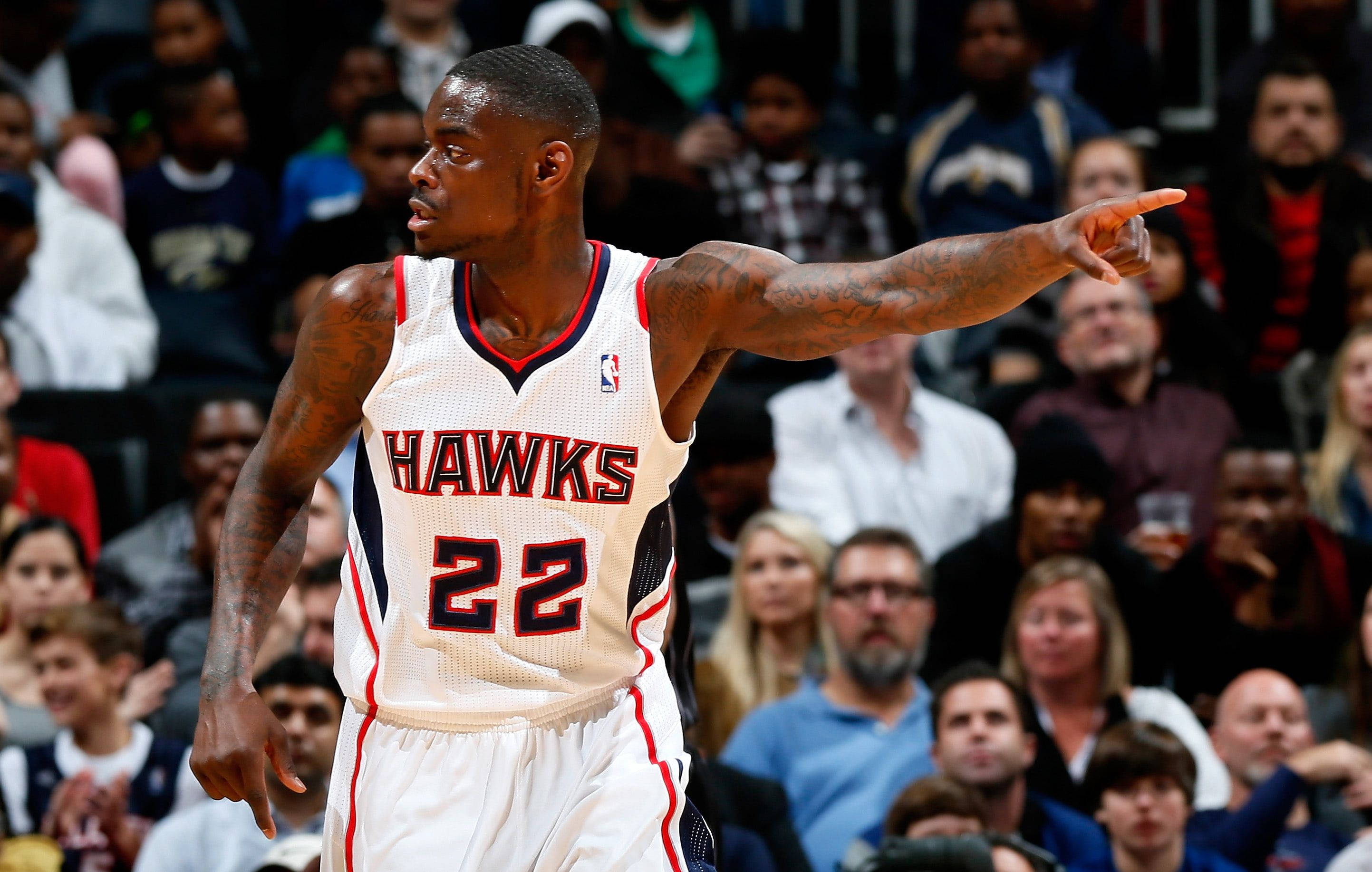 Hawks 桌布 壁紙 — 一名身穿白色老鷹隊球衣、背號22的籃球運動員在比賽中向前指，背景有群眾。