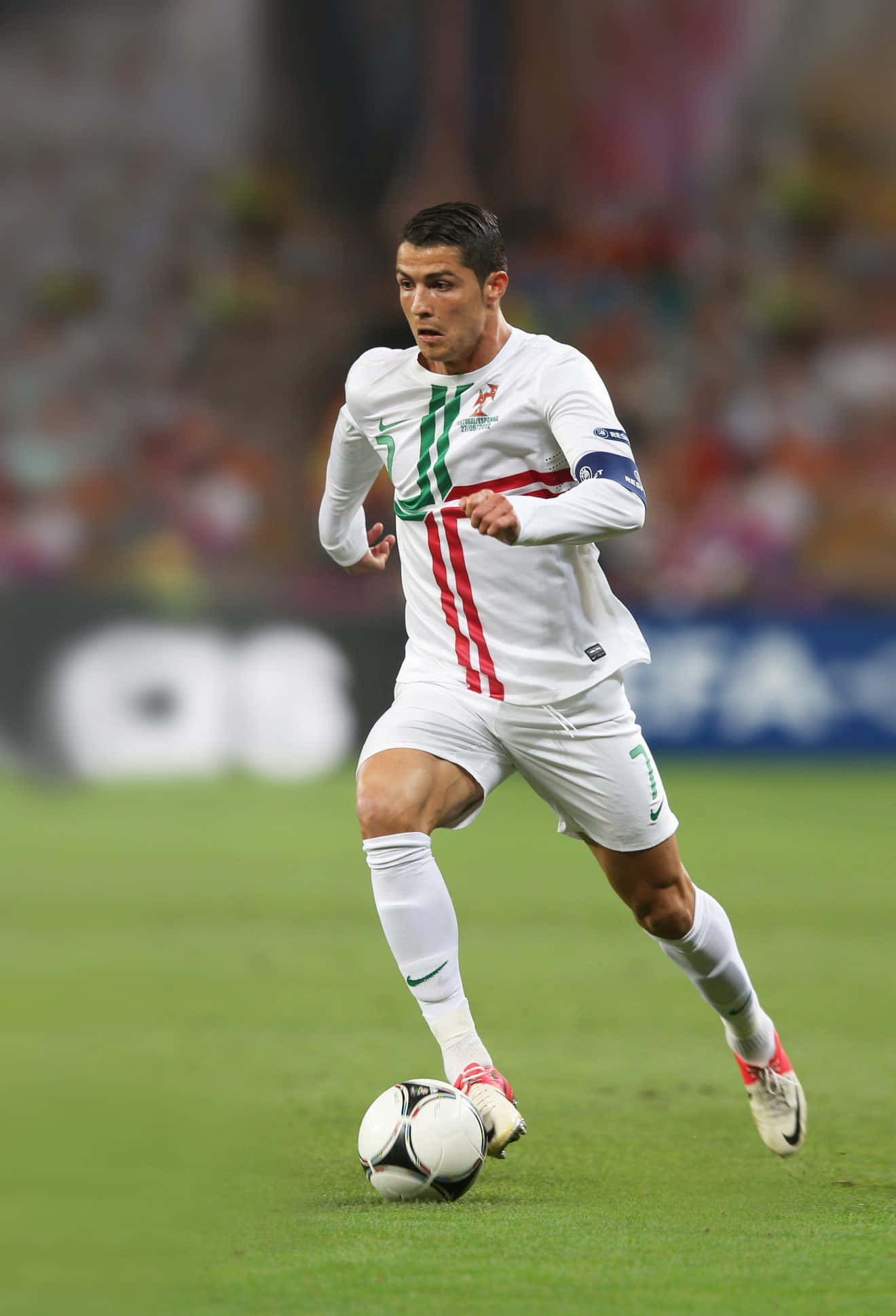 Ronaldo 桌布 壁紙 — 一名身穿白色葡萄牙球衣的足球運動員在體育場燈光下於充滿活力的綠色球場上盤帶黑白足球。