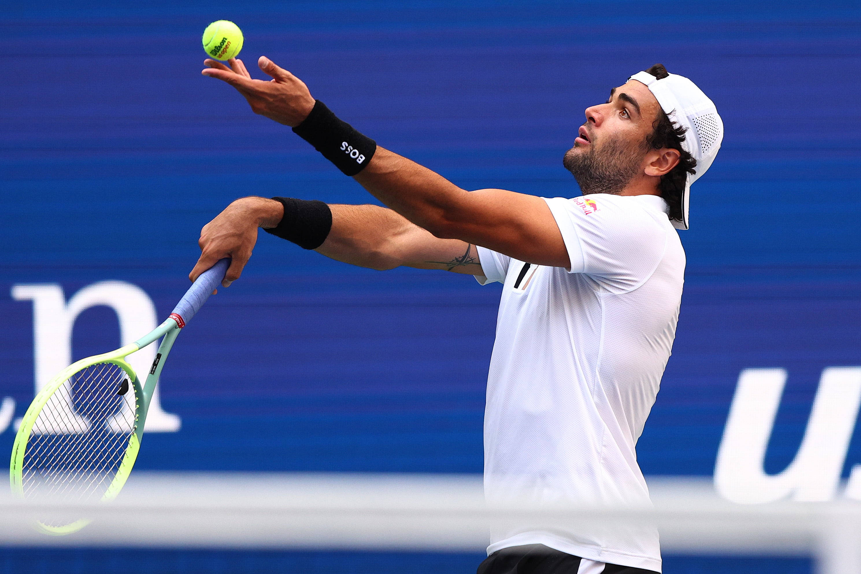 Tennis 桌布 壁紙 — 一名身穿白色裝備的男性網球選手將一顆亮黃色的球拋向空中，準備在純藍色球場背景下發球。