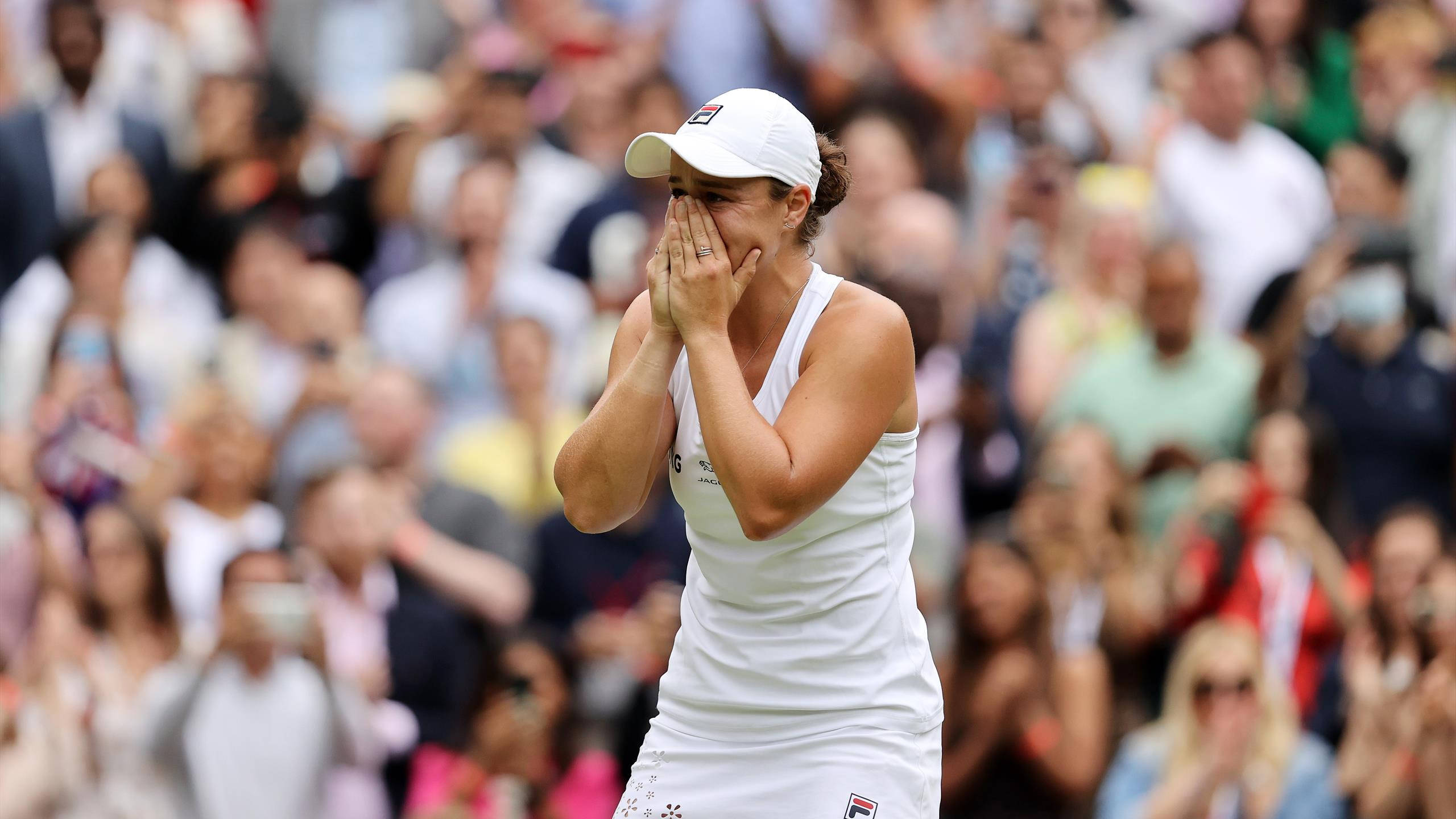 Ashleigh Barty 桌布 壁紙 — 一名身穿白色裝備的網球選手在情感勝利的瞬間掩面，背後是模糊的歡呼人群。