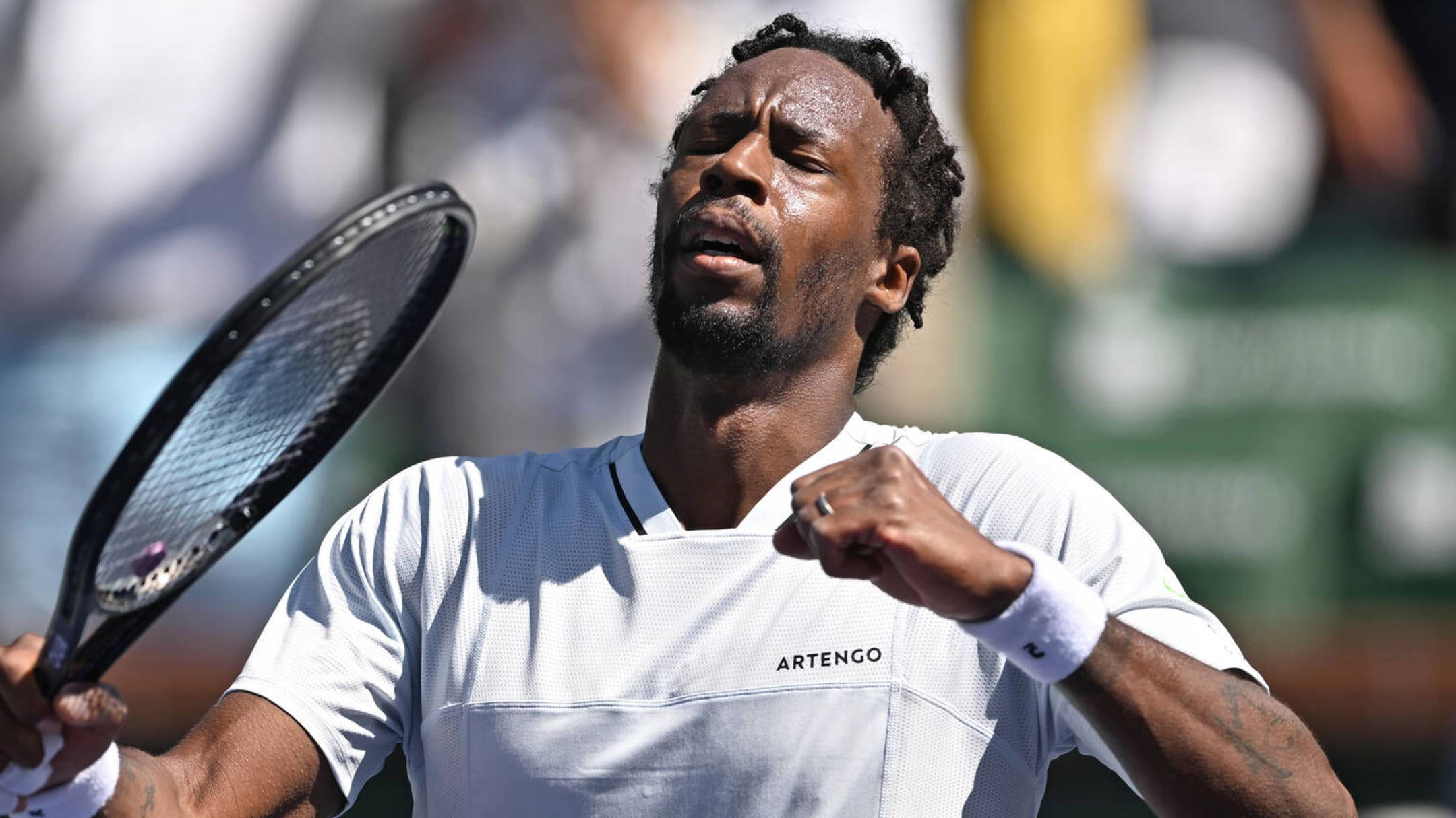 Tennis 桌布 壁紙 — 一名身穿白色襯衫的男網球運動員在明亮的陽光下握緊拳頭，高舉球拍，發出勝利的咆哮。