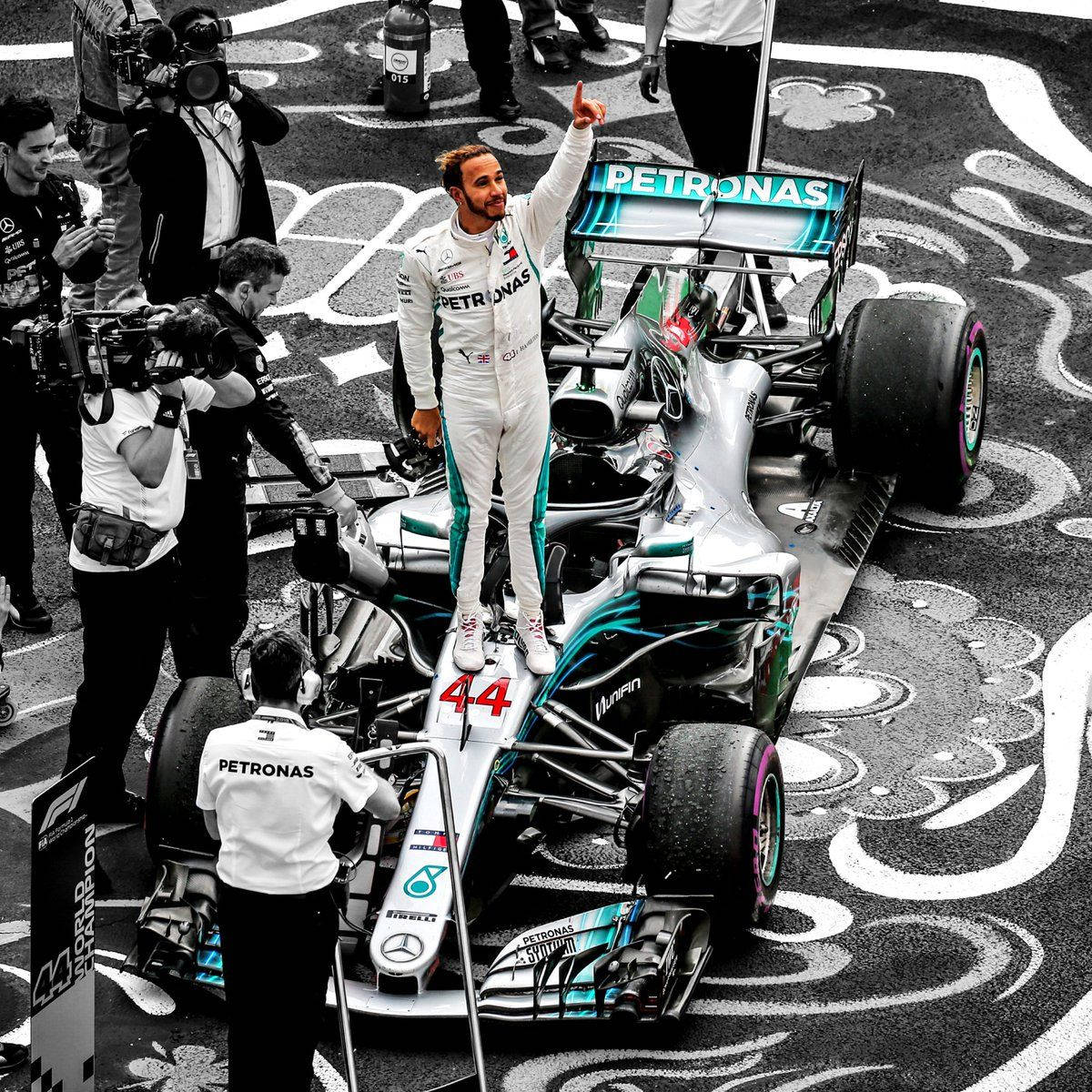 waving 桌布 壁紙 — 一名身穿白色賽車服的F1車手，單手高舉，勝利地站在他的銀色Mercedes Petronas賽車上，周圍是攝影師和工作人員，背景是格子賽道。
