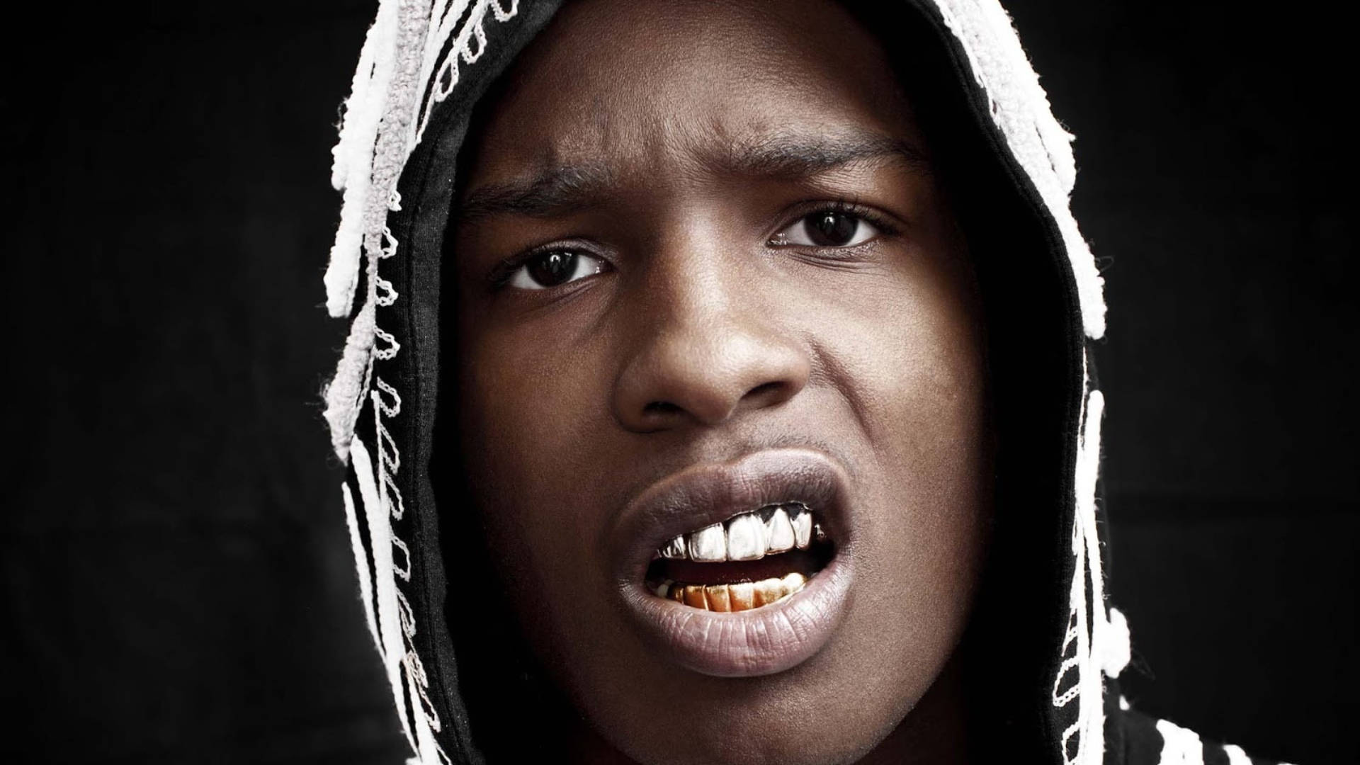 rocky 桌布 壁紙 — 一名身穿白色連帽外套的年輕男子在黑色背景前露出金牙，呈現強烈的特寫鏡頭。