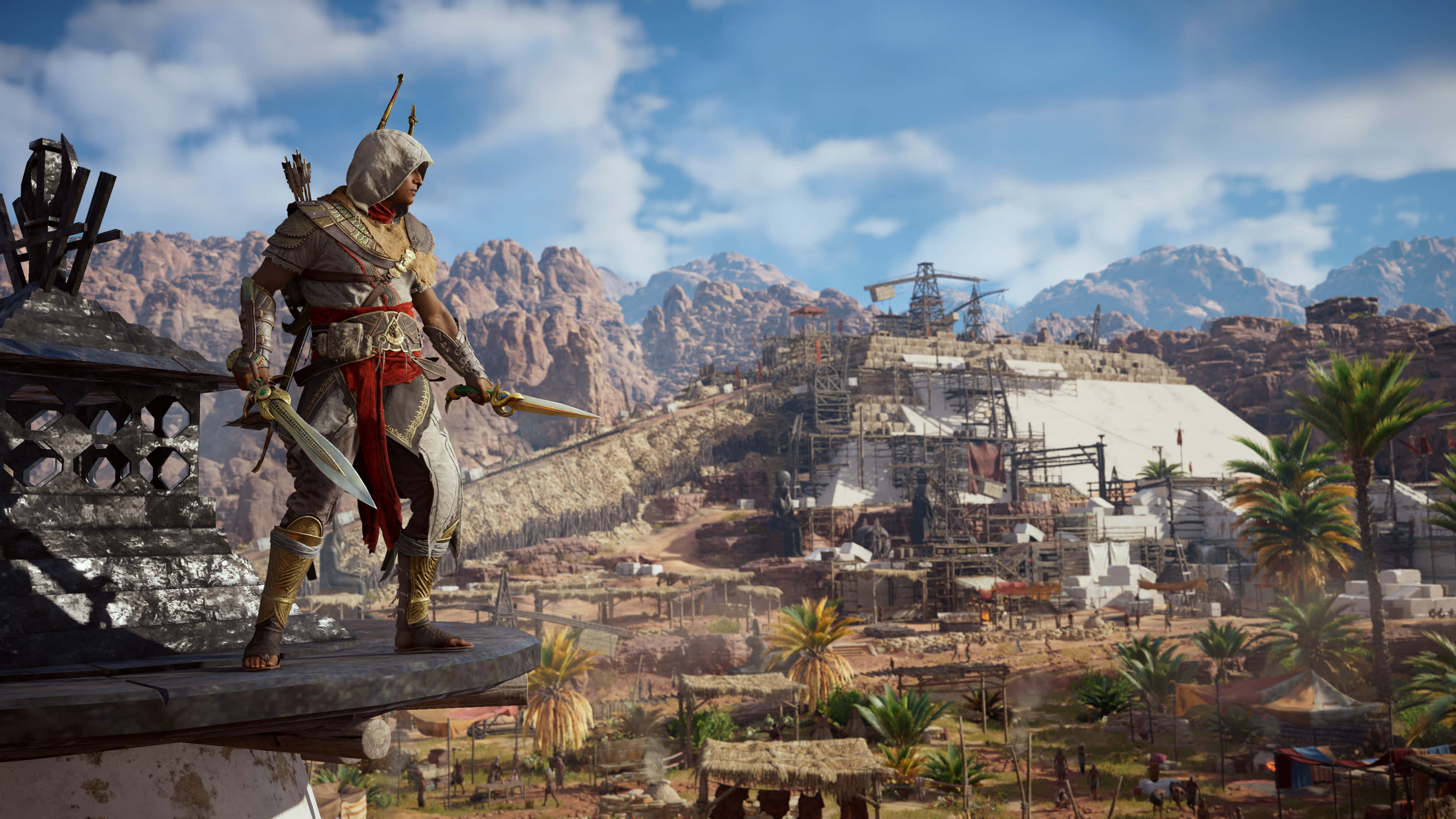 Bayek 桌布 壁紙 — 一名身穿白色連帽衫和紅色腰帶的刺客站在屋頂上，俯瞰著一個有棕櫚樹和遠山的沙漠村莊，天空湛藍明亮。