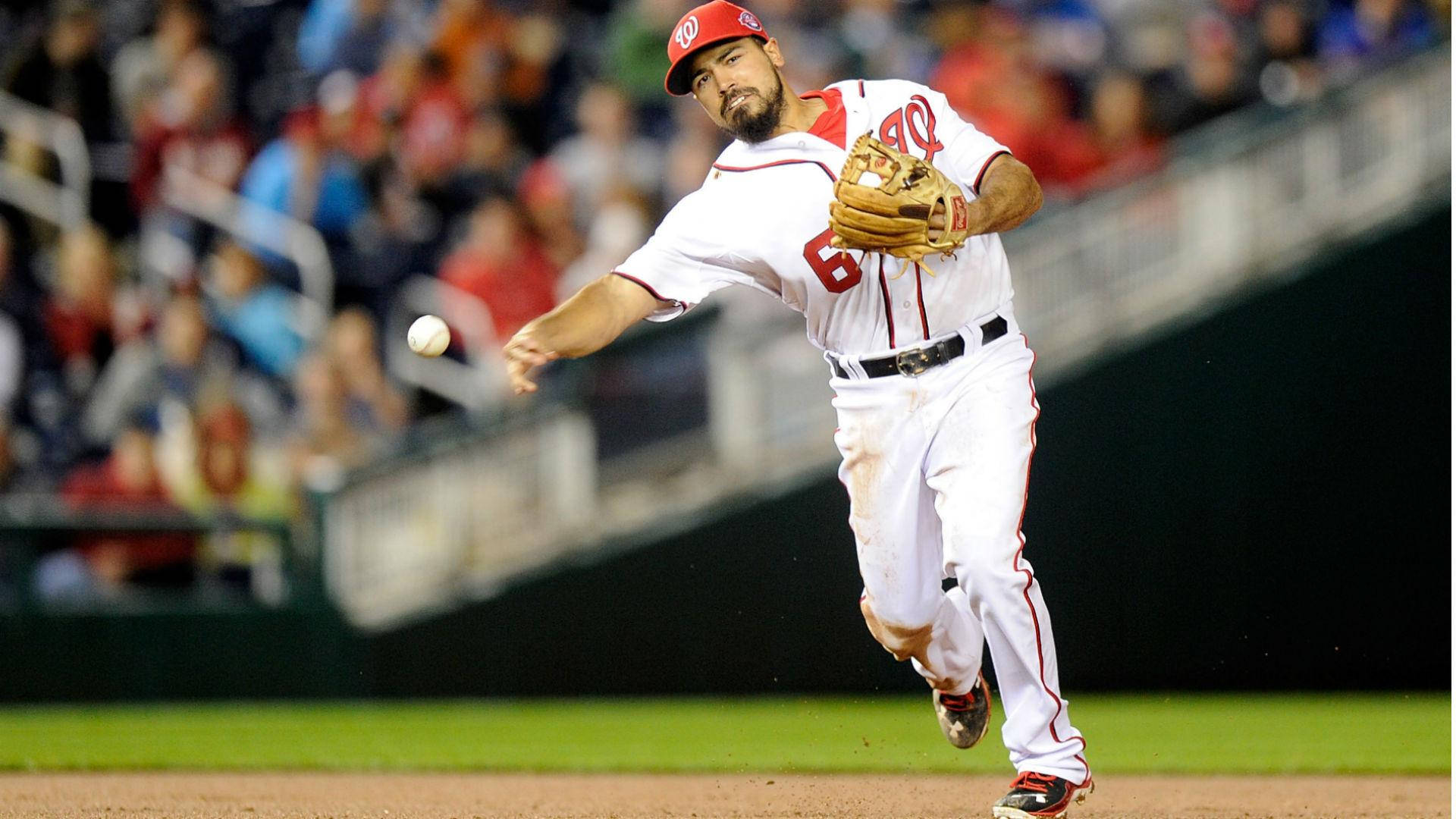 anthony rendon 桌布 壁紙 — 一名身穿白色配紅色點綴球衣的棒球投手，在夜間比賽中投球，背景是模糊的觀眾。