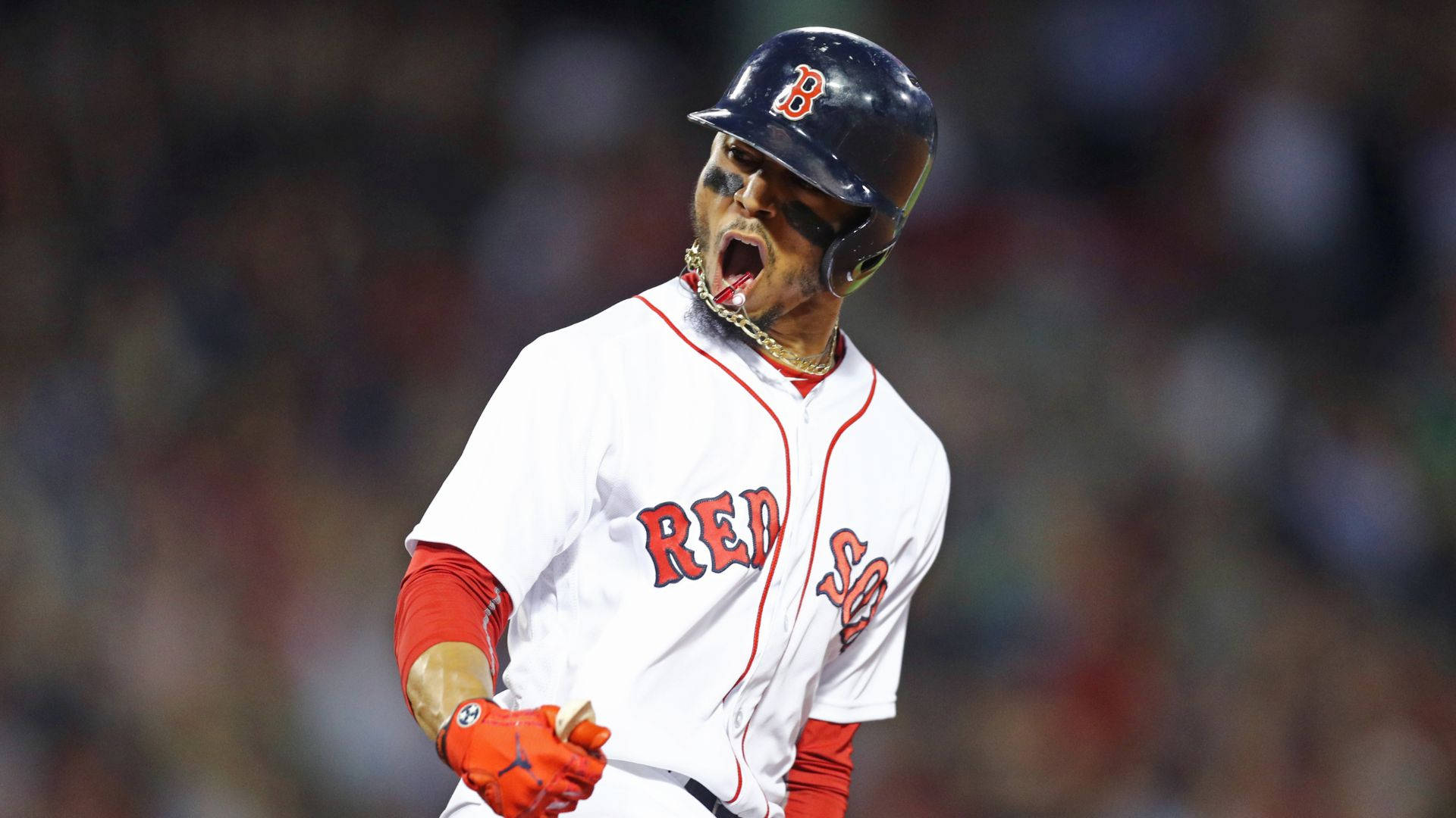 Mookie Betts 桌布 壁紙 — 一名身穿白色配紅色點綴球衣的波士頓紅襪棒球選手，在夜間比賽的球場燈光下勝利地大喊。