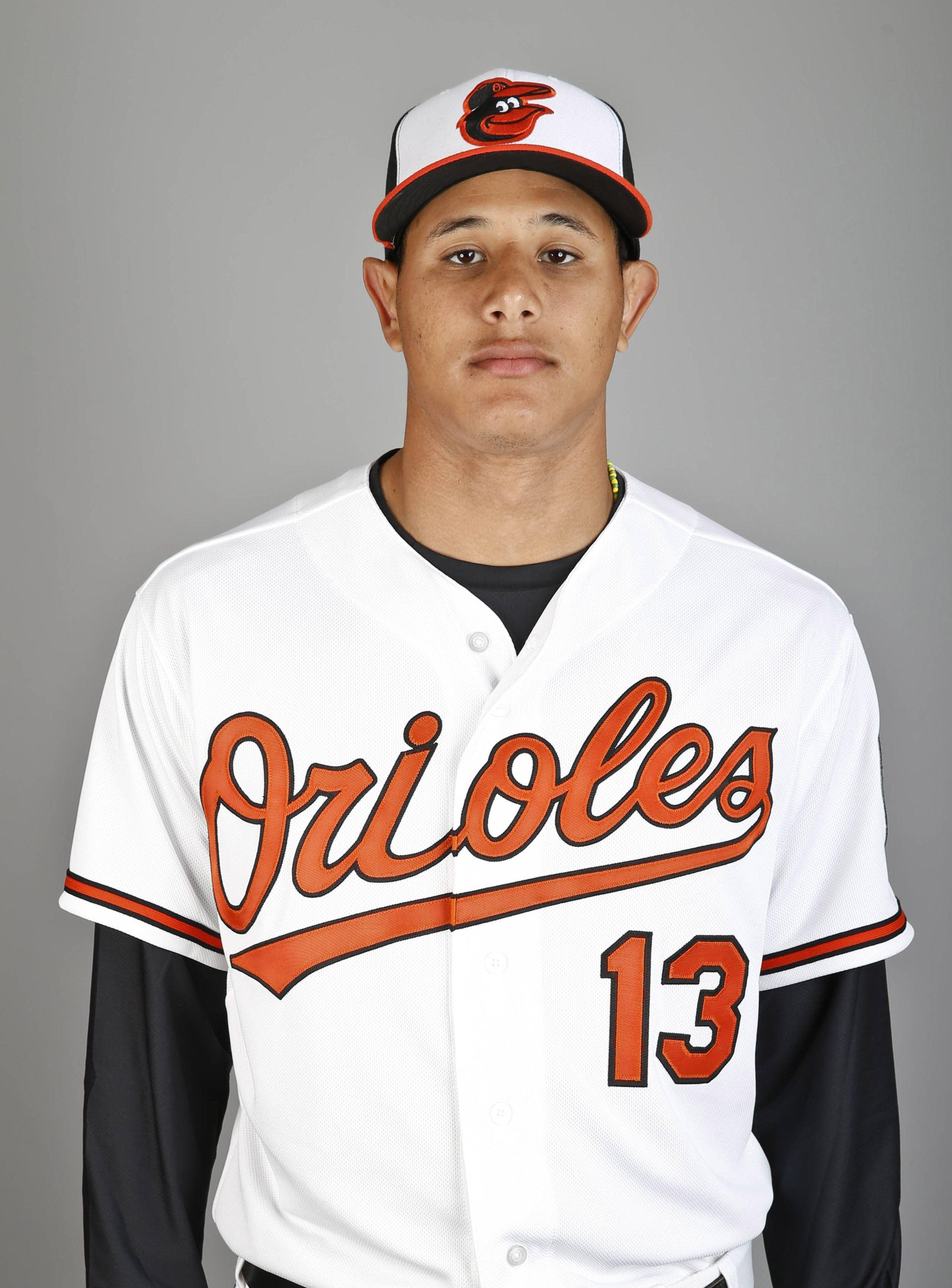 Machado 桌布 壁紙 — 一名身穿白色金鶯隊球衣、帶有橙色字體和13號的棒球運動員，在純灰色工作室背景前擺姿勢。