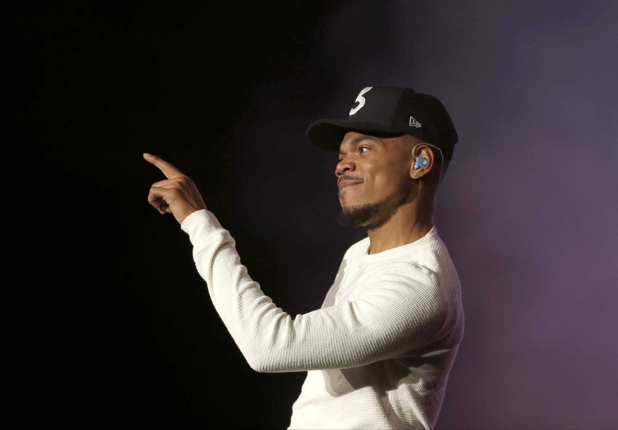 chance 桌布 壁紙 — 一名身穿白色長袖襯衫和黑色帽子的男子，在深紫色燈光背景下自信地指著。