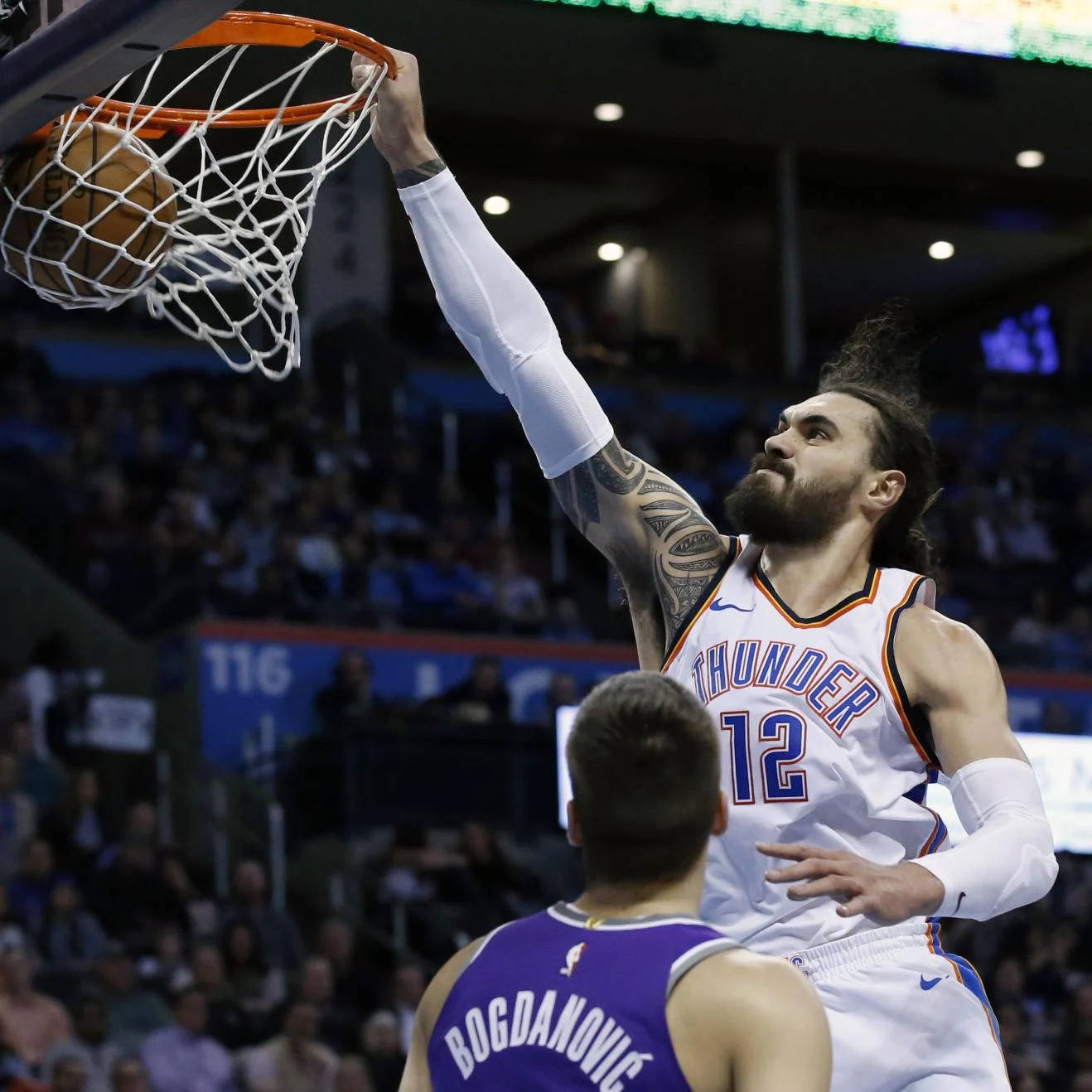 Steven Adams 桌布 壁紙 — 一名身穿白色雷霆球衣的籃球運動員大力灌籃，對手從下方觀看。