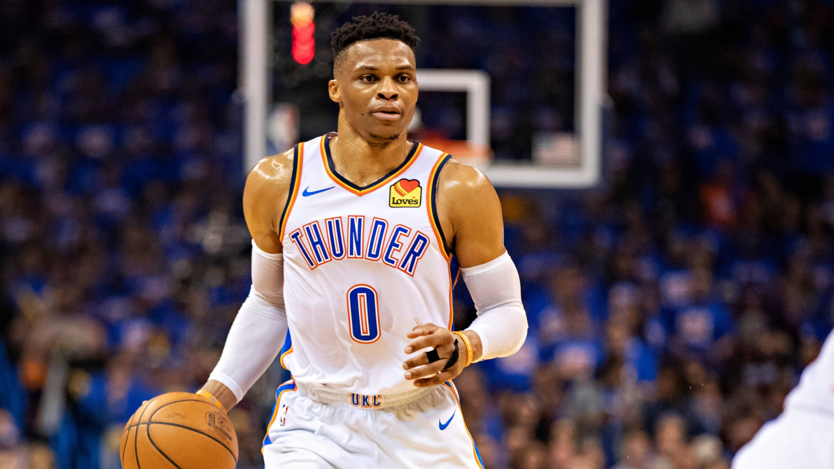 Westbrook 桌布 壁紙 — 一名身穿白色雷霆隊球衣的籃球運動員在明亮的場館燈光下運球比賽。