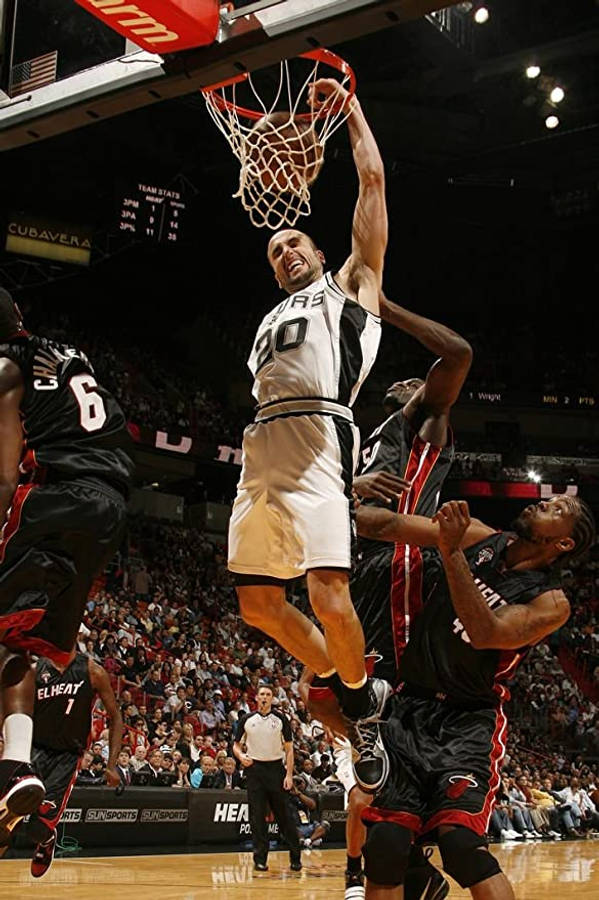 Manu 桌布 壁紙 — 一名身穿白色馬刺球衣的籃球運動員在擠滿觀眾的場館中，專注地灌籃，而身穿黑色球衣的防守球員試圖阻擋他。