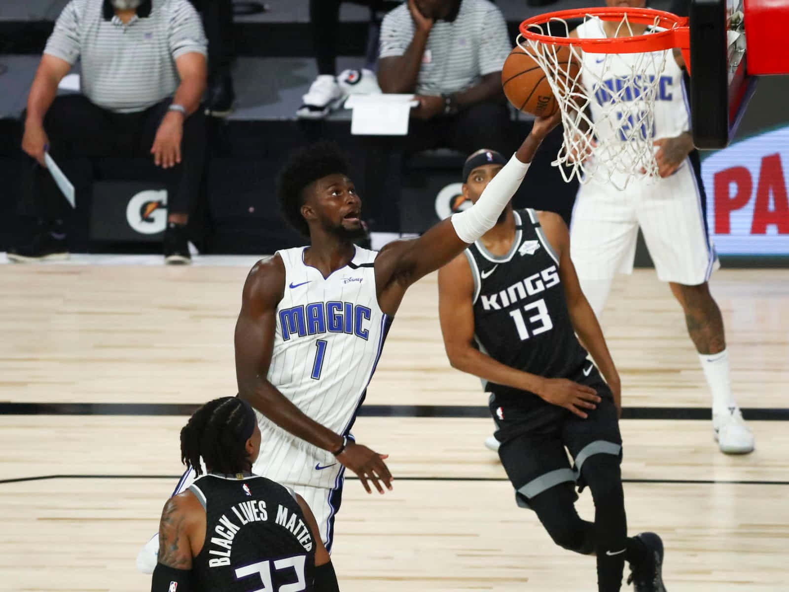 Orlando Magic 桌布 壁紙 — 一名身穿白色魔術隊球衣的籃球運動員正在灌籃，而一名身穿黑色的國王隊防守球員試圖封阻。