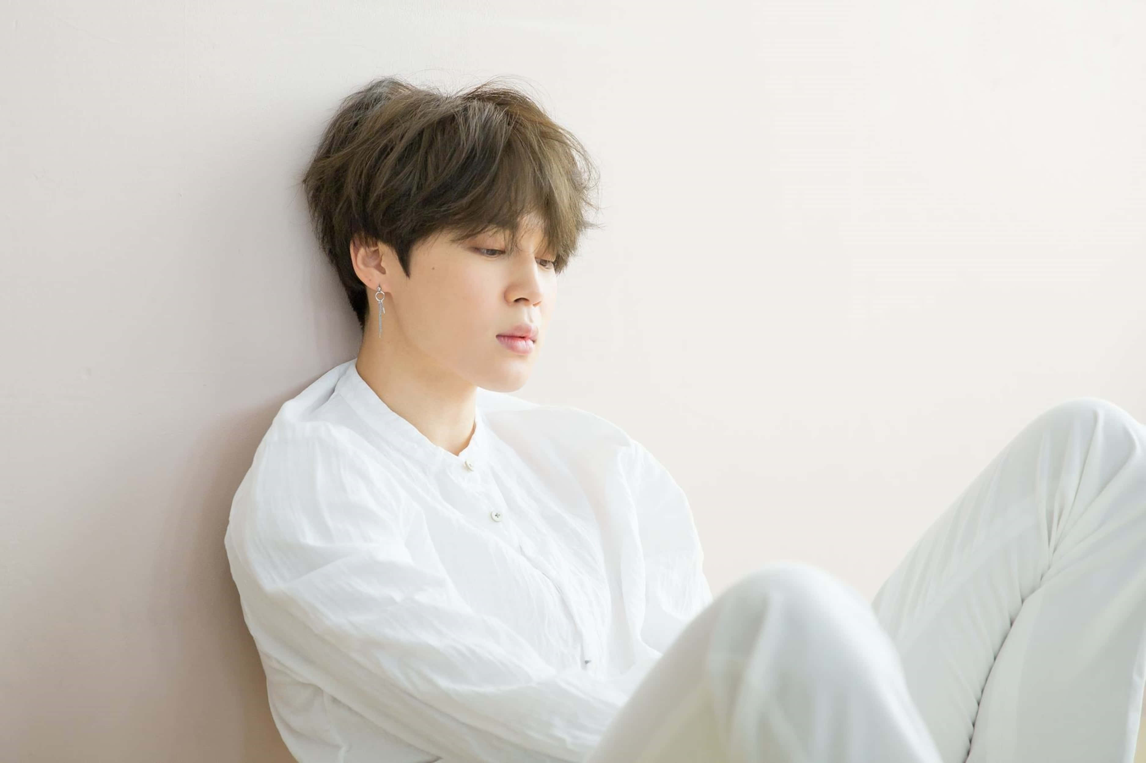BTS 桌布 壁紙 — 一名身穿白衣的年輕男子靠著素牆，閉目靜憩。