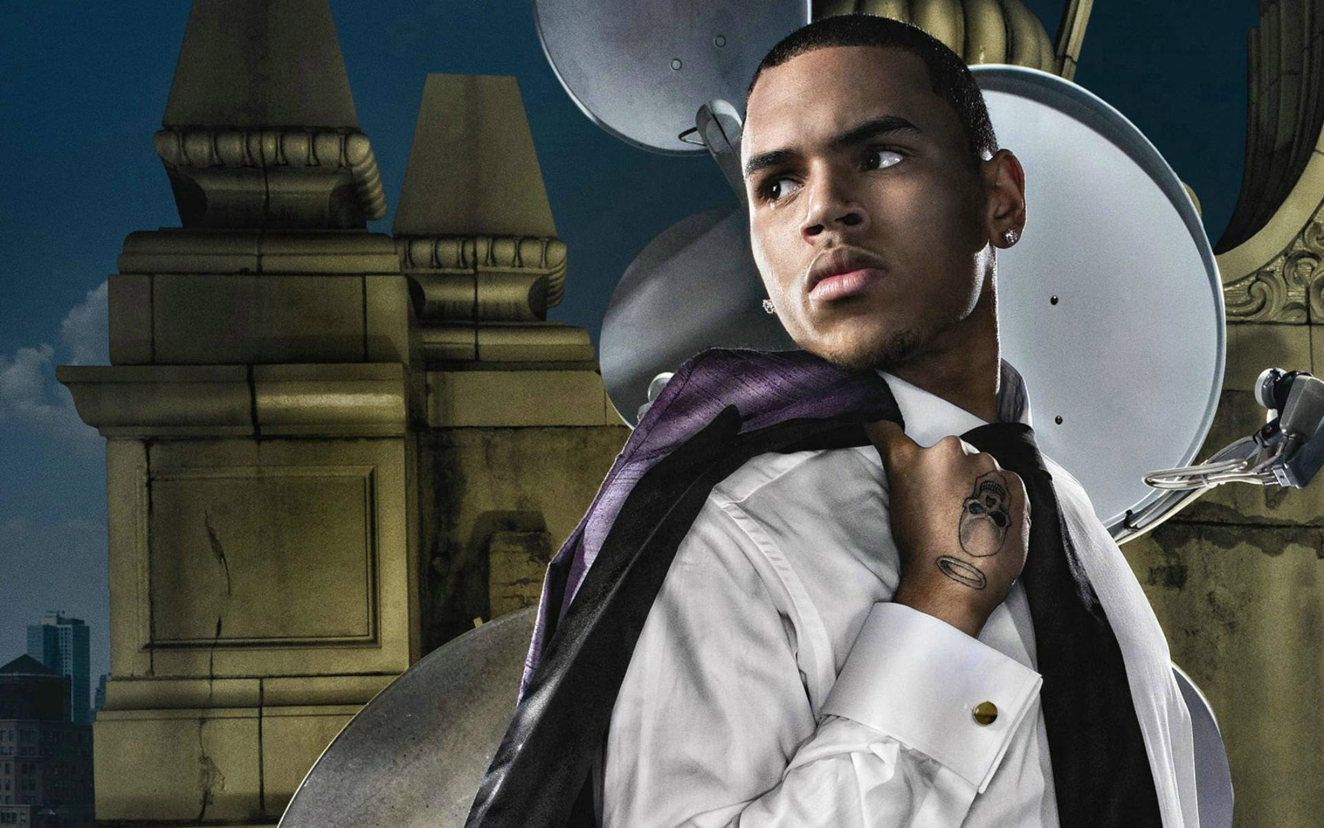 Chris Brown 桌布 壁紙 — 一名身穿白襯衫和紫色領帶的男子，在暮色天空下，以衛星天線和石頭建築為背景，自信地站立。