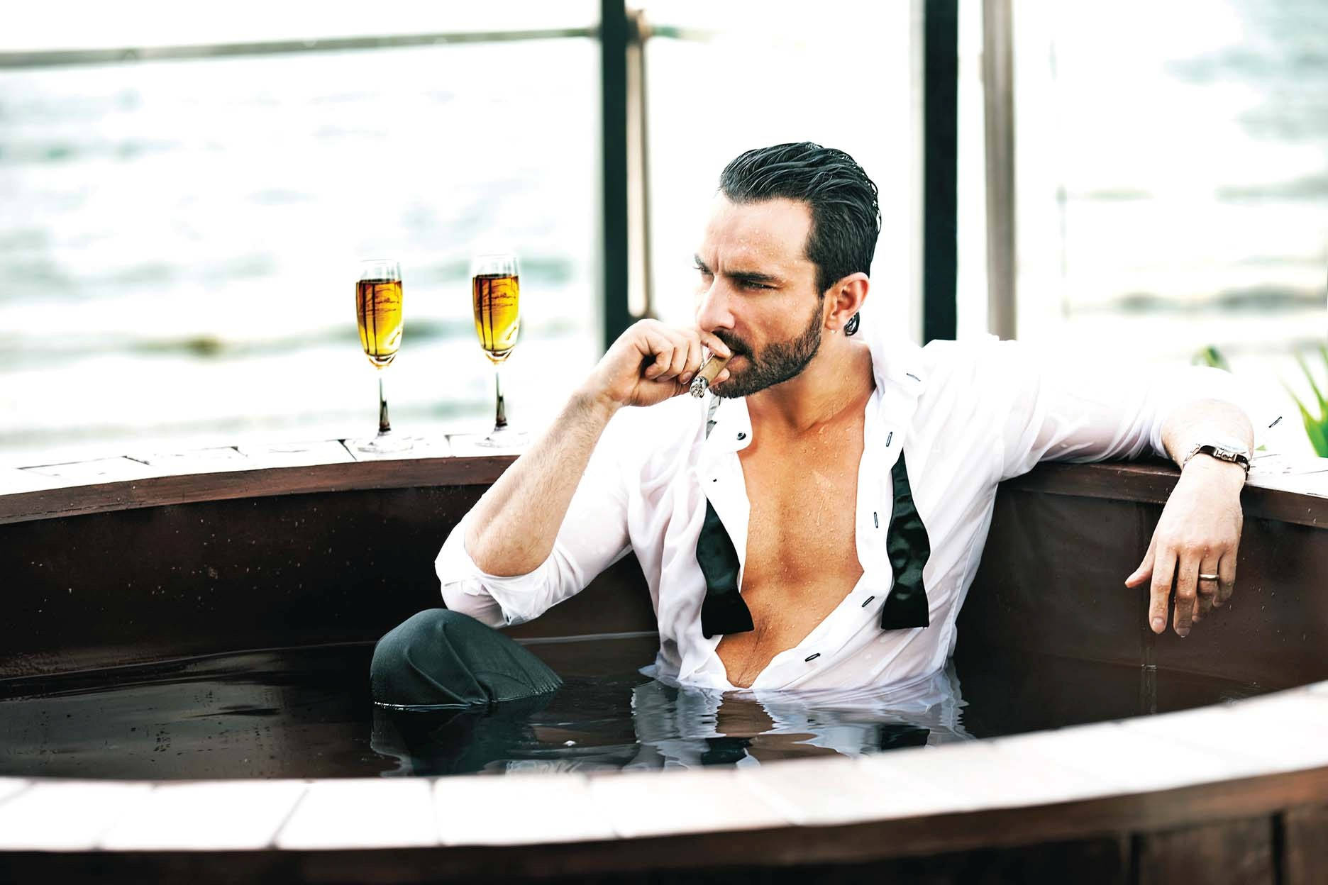 Saif Ali Khan 桌布 壁紙 — 一名身穿白襯衫的男子在按摩浴池中放鬆，旁邊有兩杯香檳，俯瞰水面。