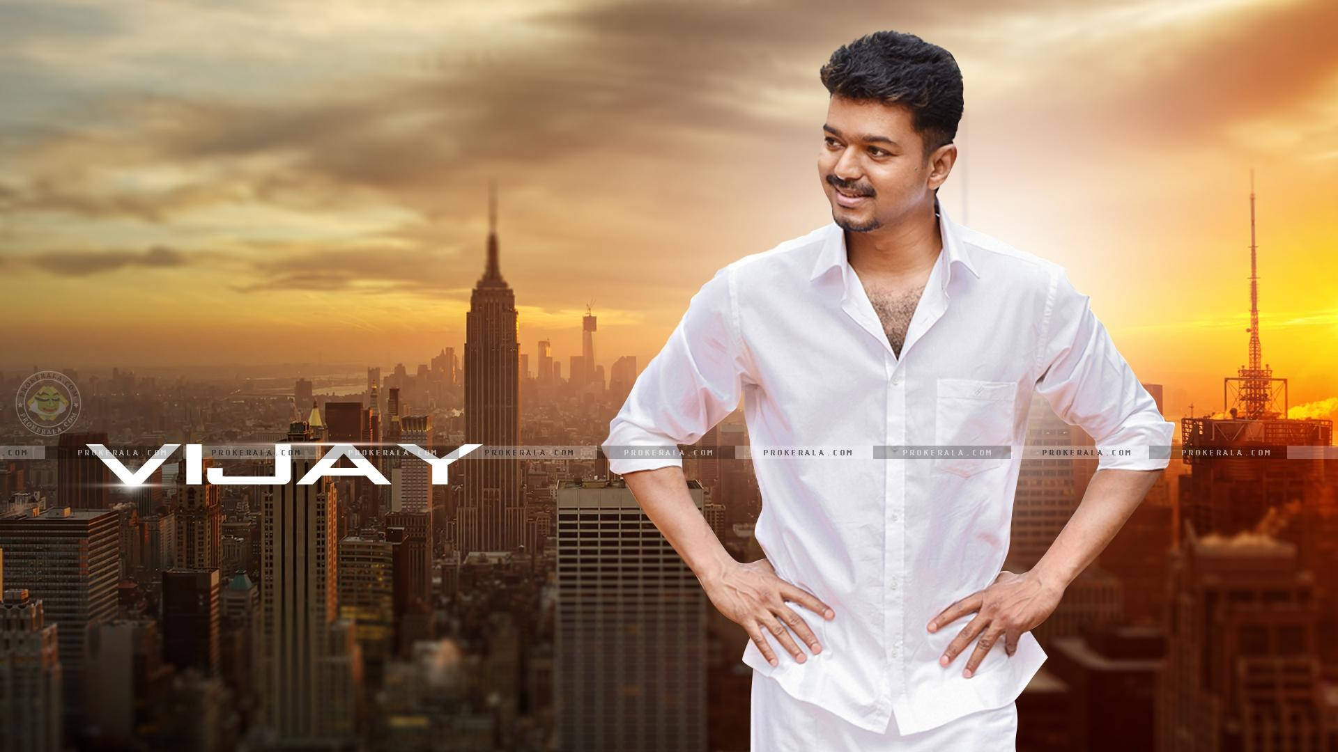vijay HD 桌布 壁紙 — 一名身穿白襯衫的男子自信地雙手叉腰，站在金色日落城市天際線前，背景是帝國大廈。