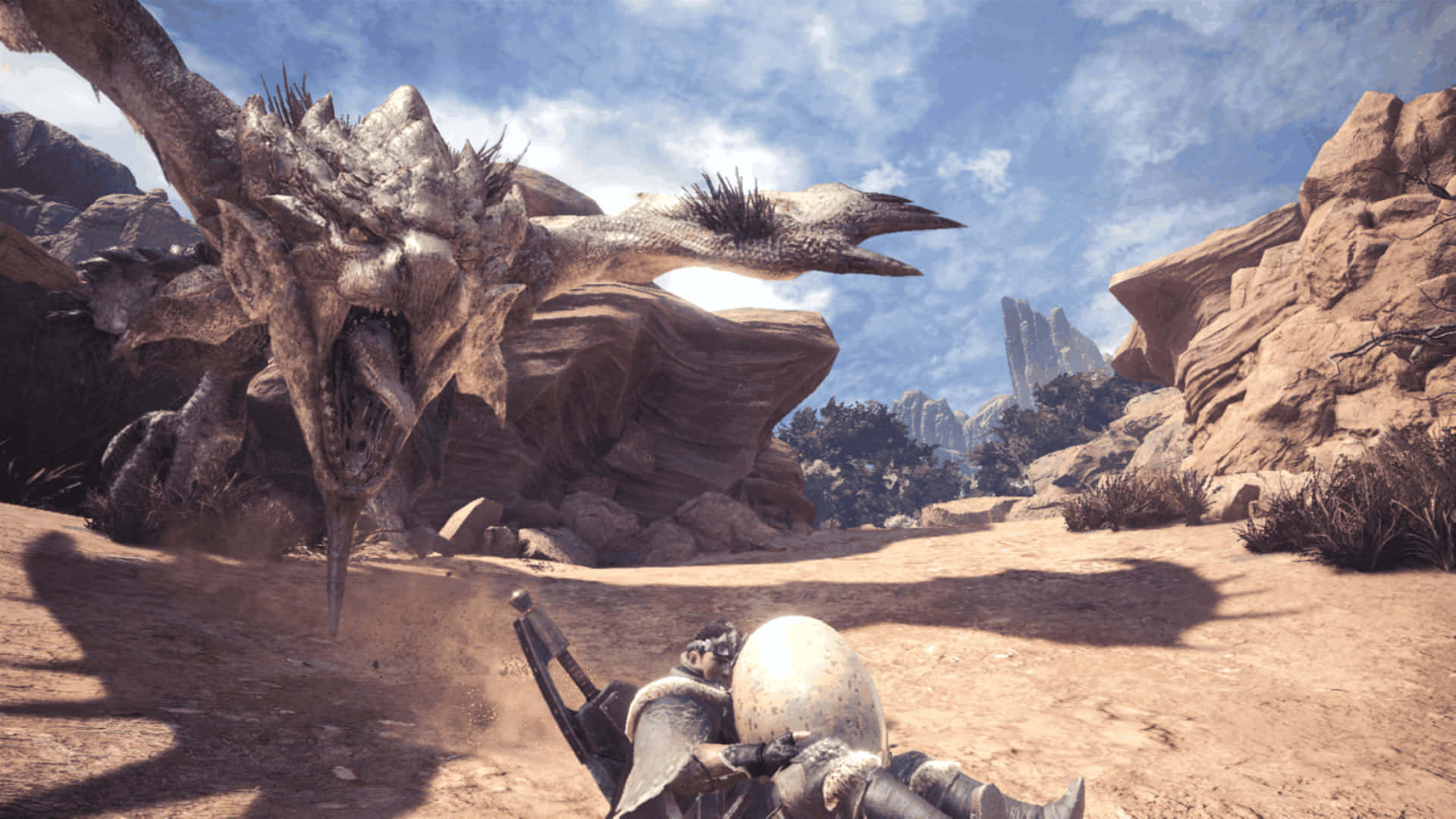 1920x1080 Monster Hunter World 桌布 壁紙 — 一名身穿盔甲的獵人在陽光明媚的岩石沙漠峽谷中面對一隻巨大的咆哮巨龍。