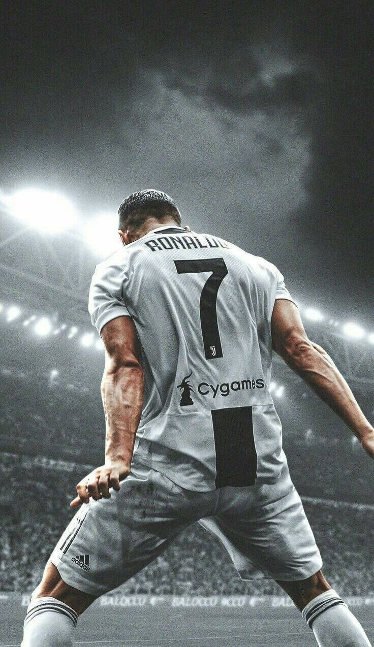 Ronaldo 桌布 壁紙 — 一名身穿祖雲達斯7號球衣的足球員站在球場上，上方有明亮的泛光燈和戲劇性的烏雲。