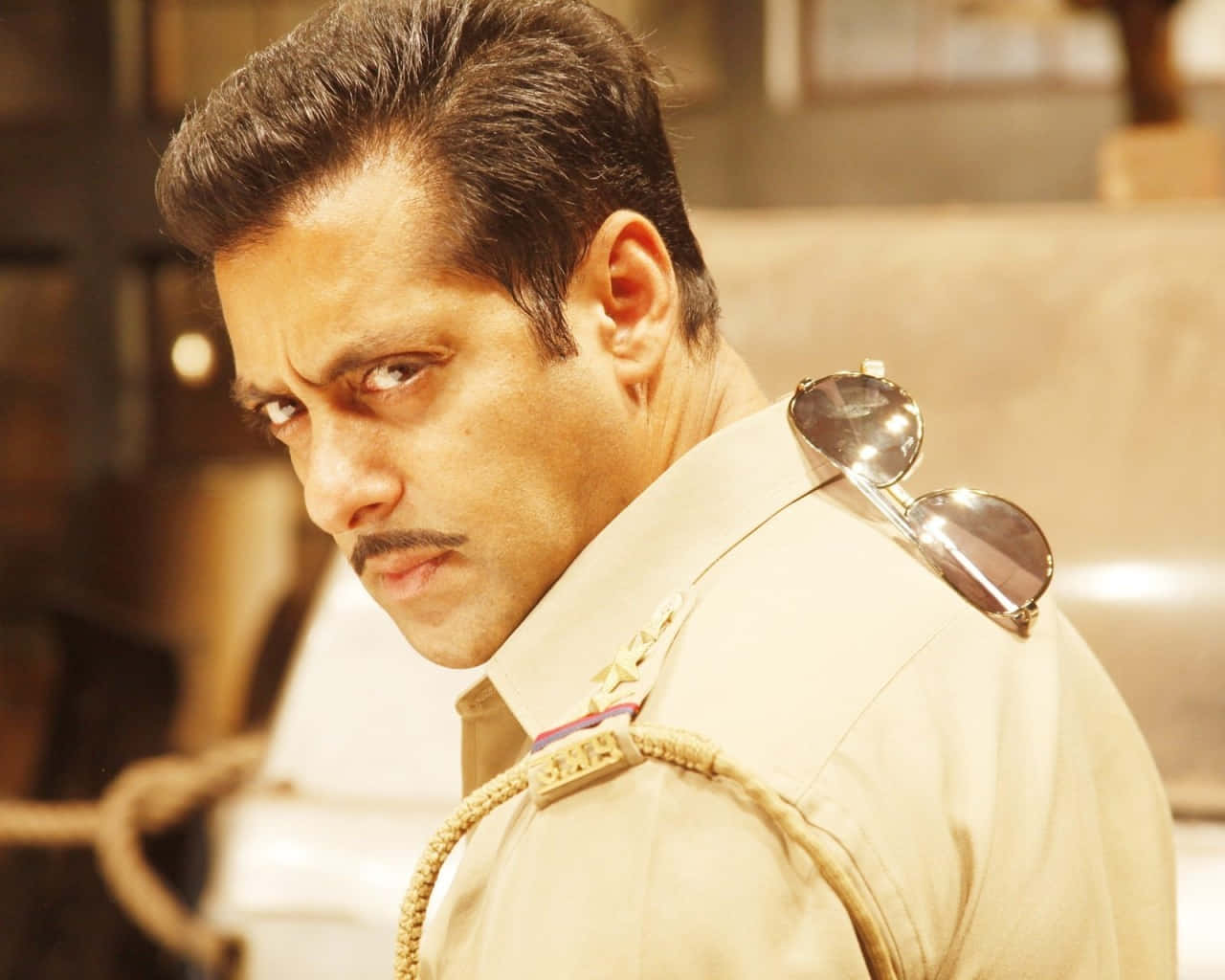 Bollywood Hero 桌布 壁紙 — 一名身穿米色制服、肩上掛著太陽眼鏡的男子，越過肩膀怒目而視。