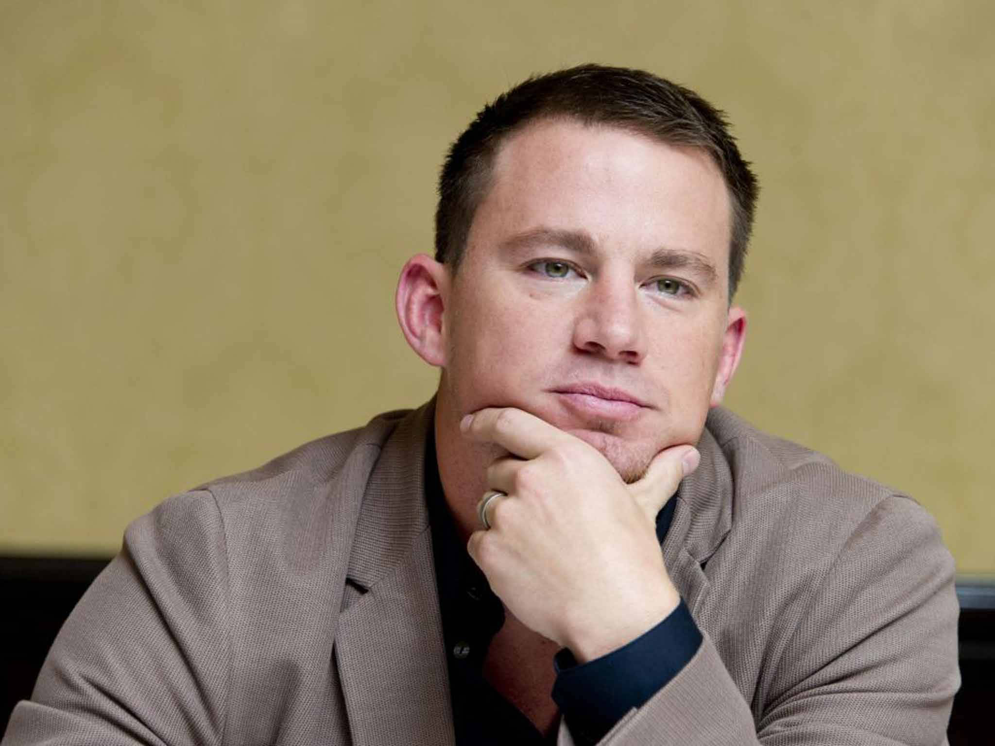 Channing 桌布 壁紙 — 一名身穿米色西裝外套的男子，將下巴擱在手上，靠著柔和的黃色牆壁。