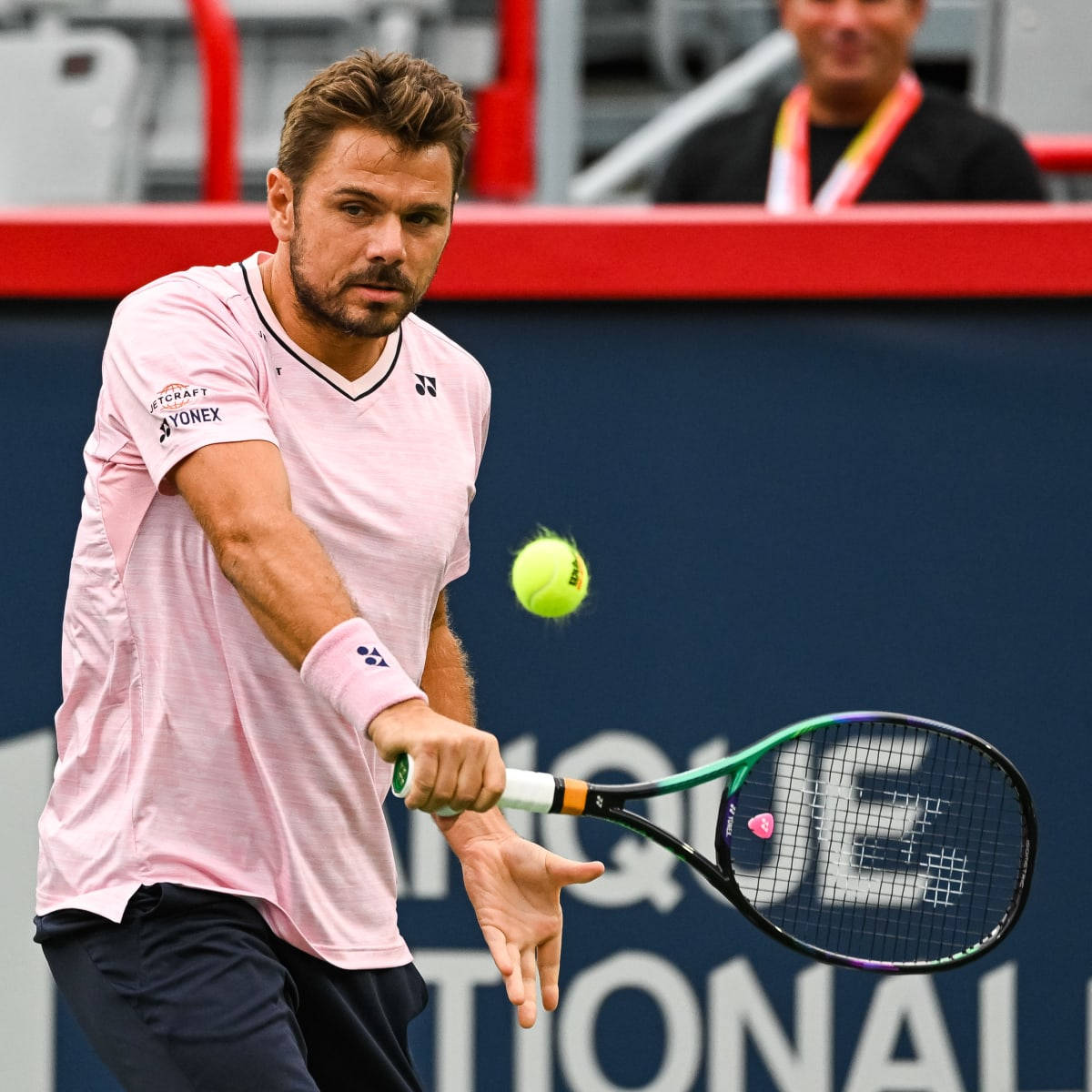 Tennis 桌布 壁紙 — 一名身穿粉紅色襯衫的男網球選手在比賽中揮動球拍擊打一個亮黃色的網球。