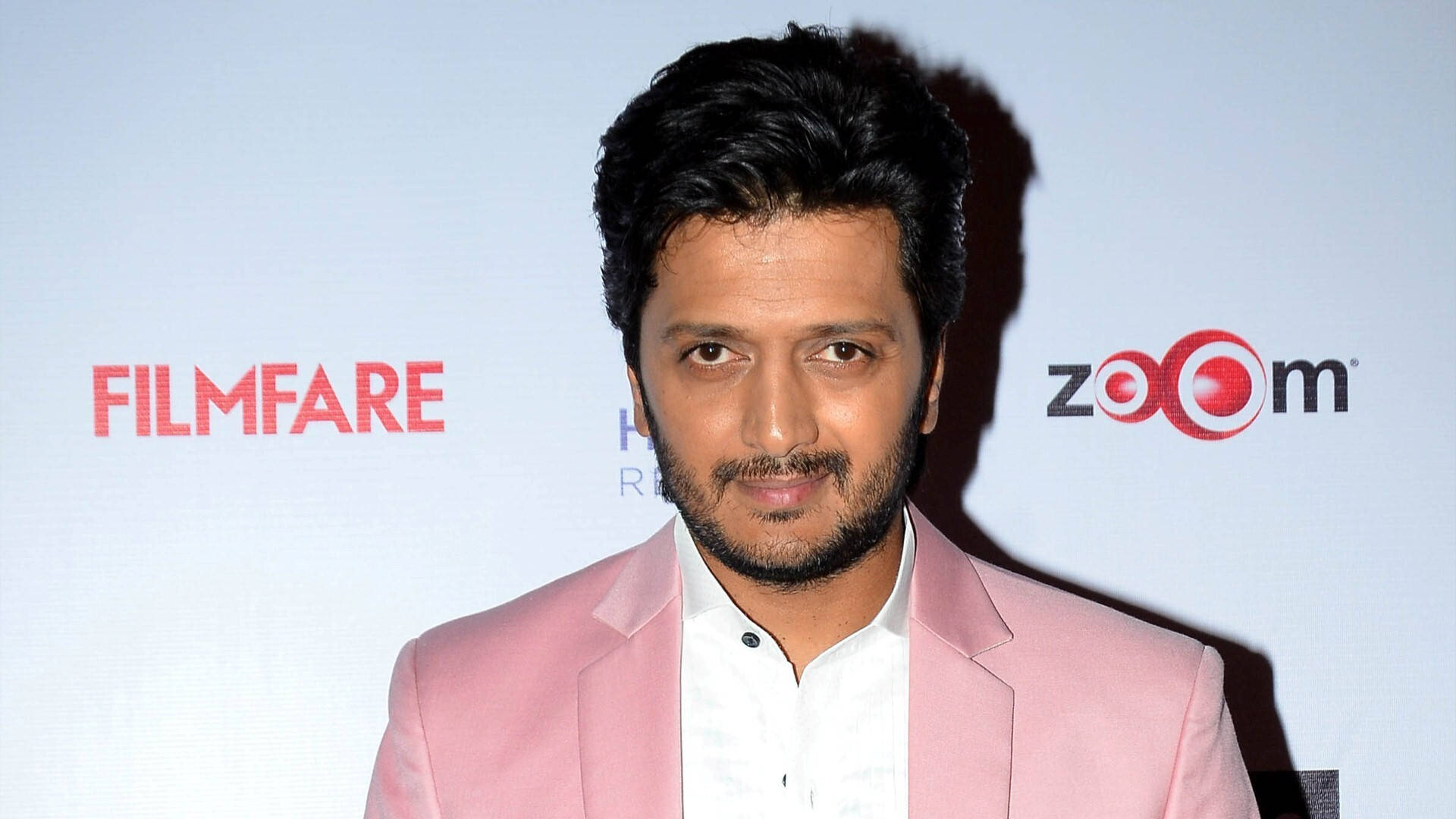 riteish deshmukh 桌布 壁紙 — 一名身穿粉紅色西裝的男子在Filmfare活動中自信地站立，背後有Zoom品牌標誌。