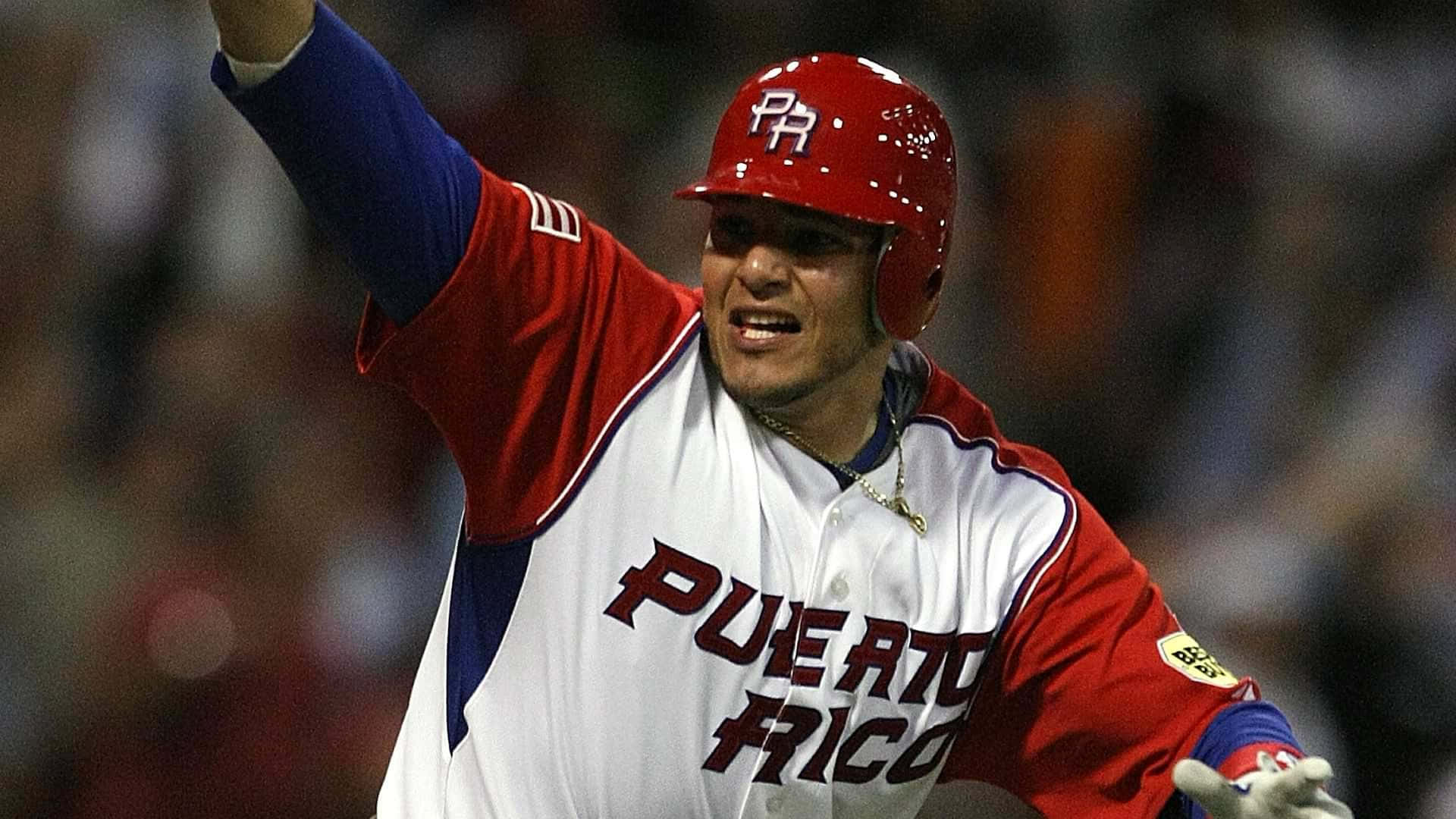 Yadier Molina 桌布 壁紙 — 一名身穿紅、白、藍色球衣的波多黎各棒球選手，在夜間比賽的球場燈光下高舉手臂慶祝勝利。