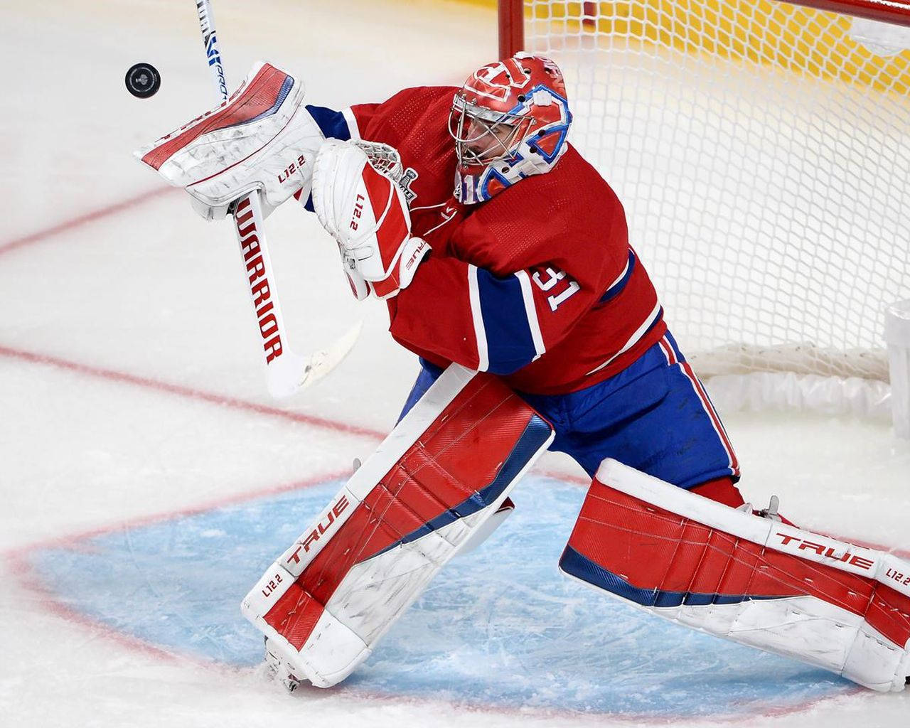 Carey Price 桌布 壁紙 — 一名身穿紅、藍、白色裝備的冰球守門員在冰上近球門處飛撲阻擋冰球。