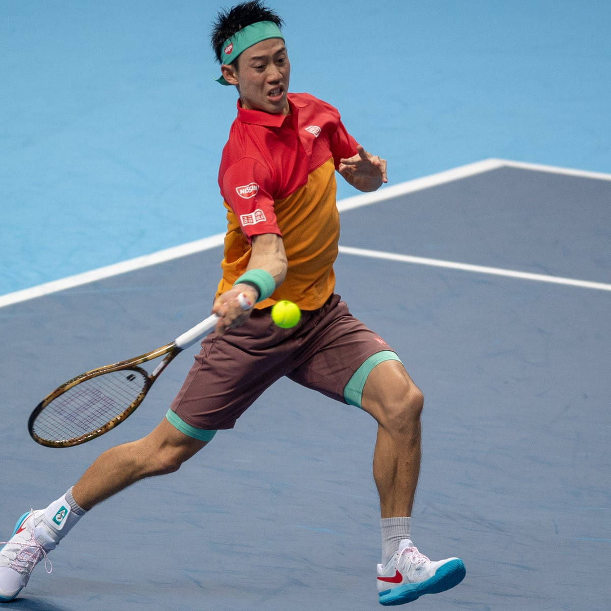 Athletic 桌布 壁紙 — 一名身穿紅橙色襯衫的男性網球選手在藍色球場上向前撲擊一顆亮黃色的球。