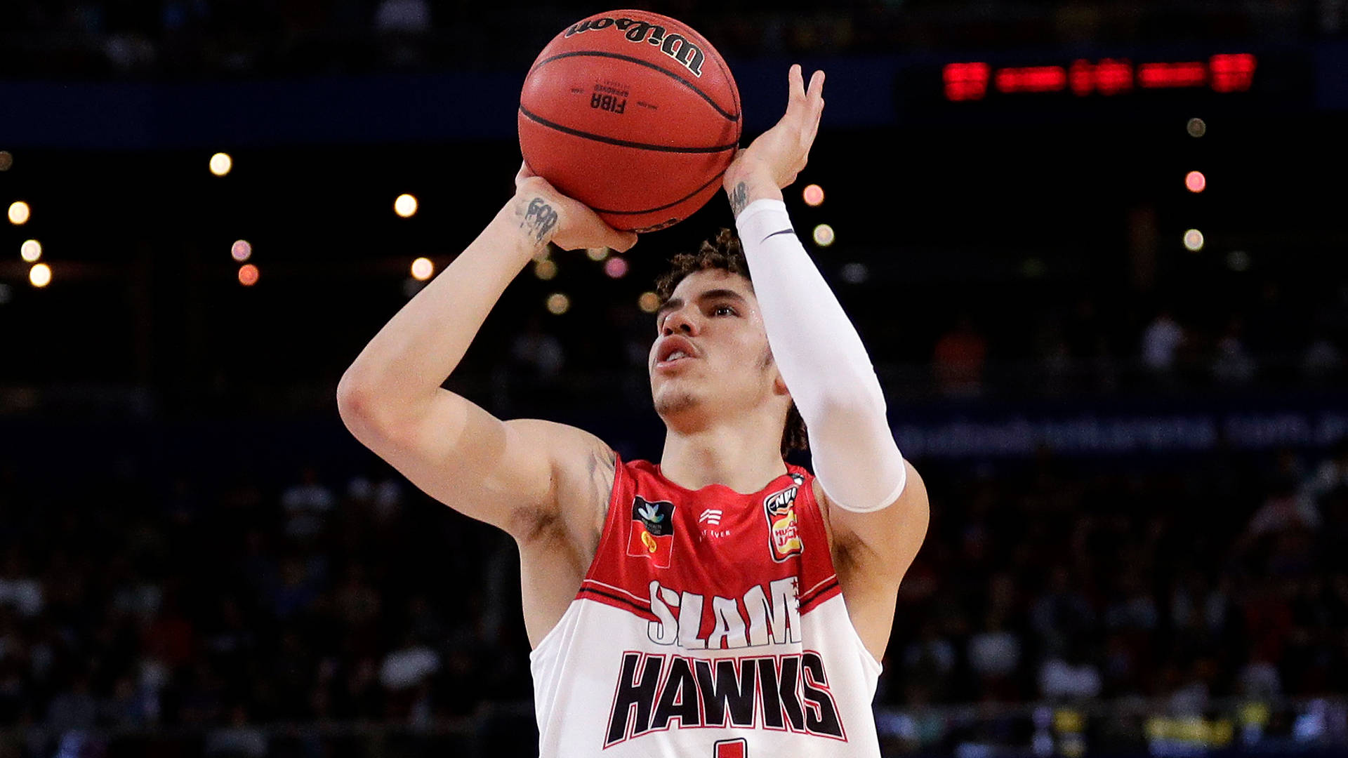 ball 桌布 壁紙 — 一名身穿紅白『SLAM HAWKS』球衣的籃球運動員在場館燈光下投出紅色Wilson球，背景有模糊的觀眾。
