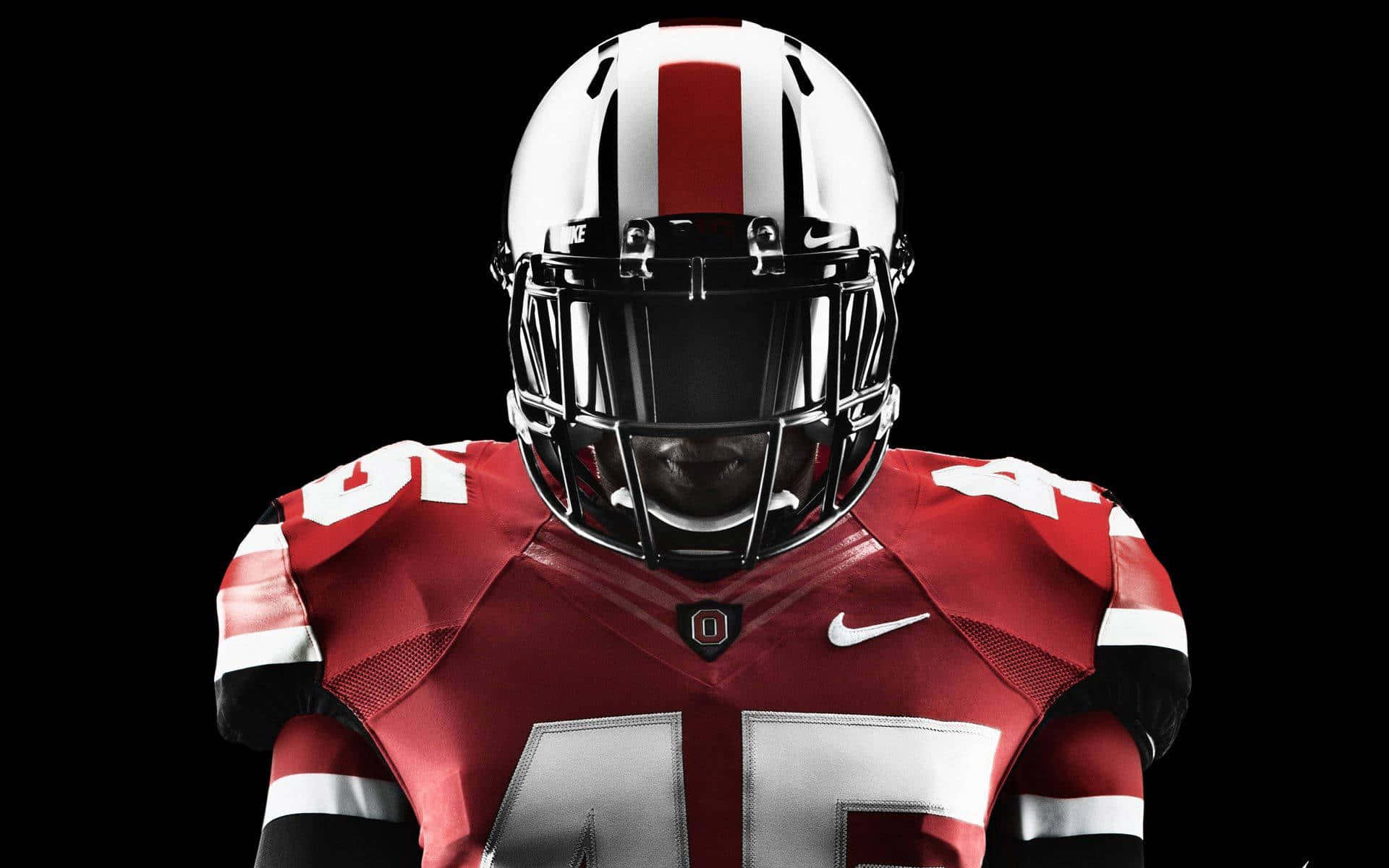 Cool Ohio State 桌布 壁紙 — 一名身穿紅白制服、戴著頭盔的美式足球運動員在黑色背景前凝視前方。