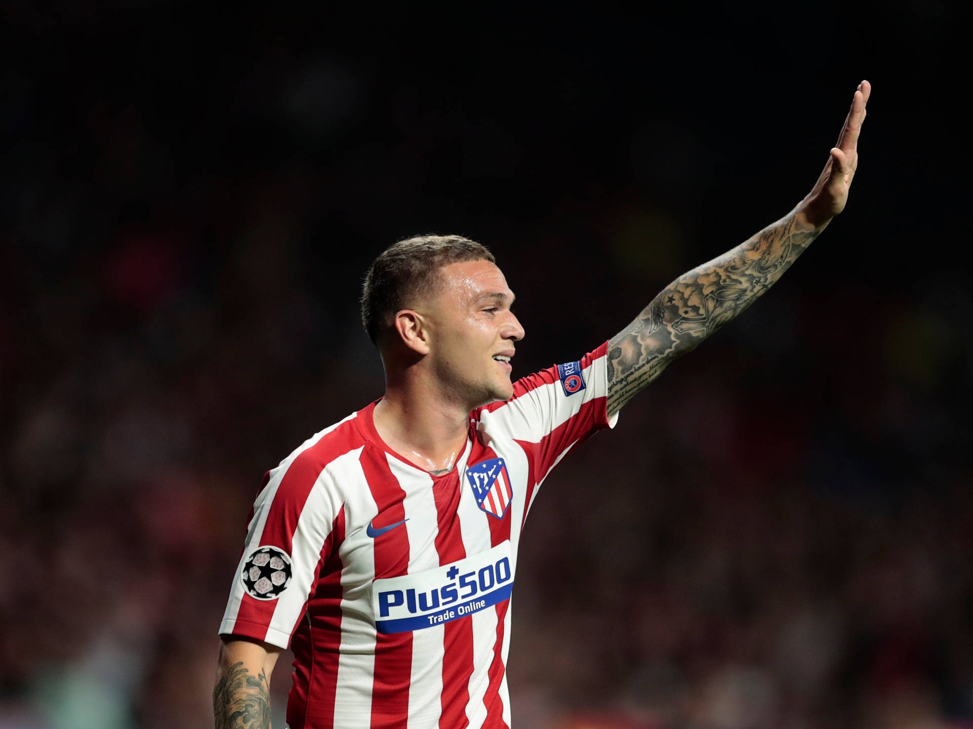 Athletic 桌布 壁紙 — 一名身穿紅白條紋球衣的足球員在球場燈光下向球迷揮手，手臂上的刺青清晰可見。