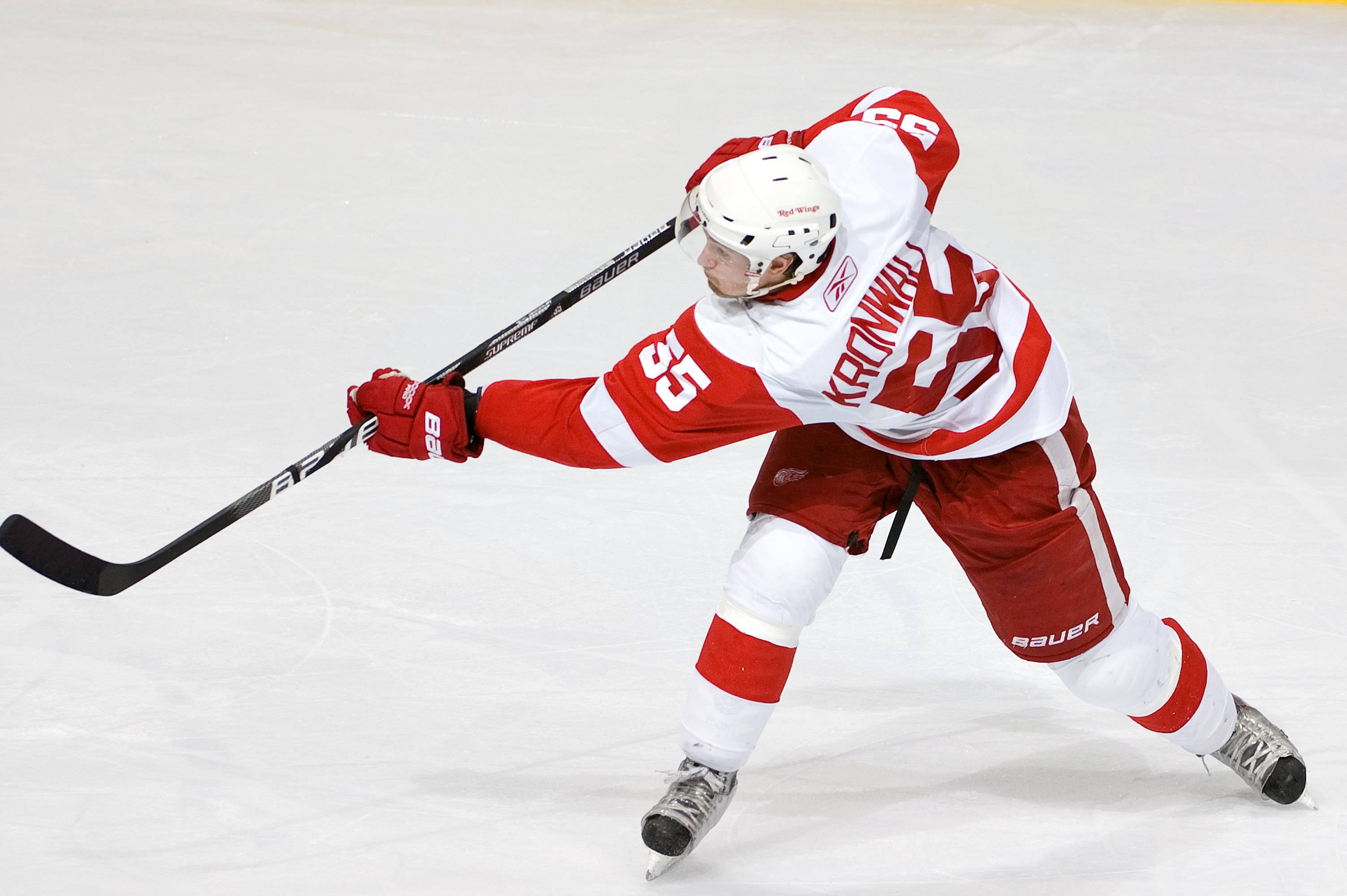 hockey 桌布 壁紙 — 一名身穿紅白球衣的冰上曲棍球運動員在比賽中低身俯在冰上，手持球棍。