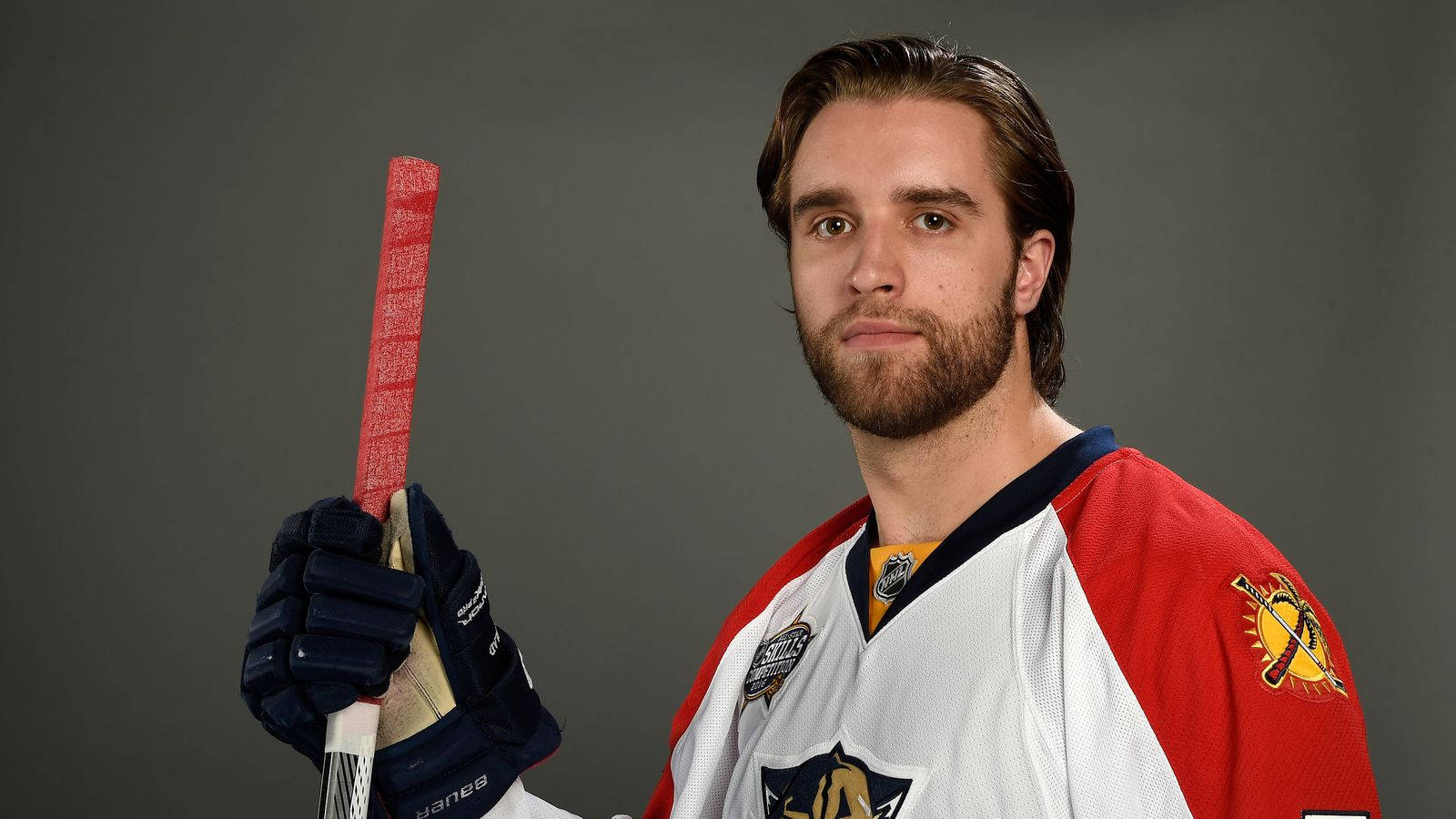 hockey 桌布 壁紙 — 一名身穿紅白球衣的曲棍球運動員在灰色工作室背景前手持球棍。