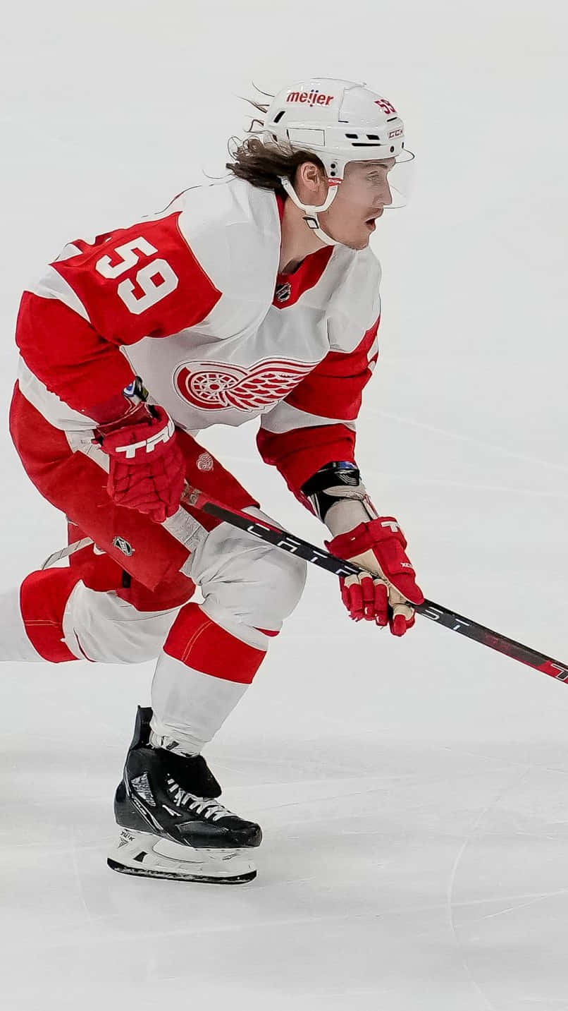 Tyler Bertuzzi 桌布 壁紙 — 一名身穿紅白球衣的曲棍球運動員在冰上低蹲，專注地握著球棍比賽。