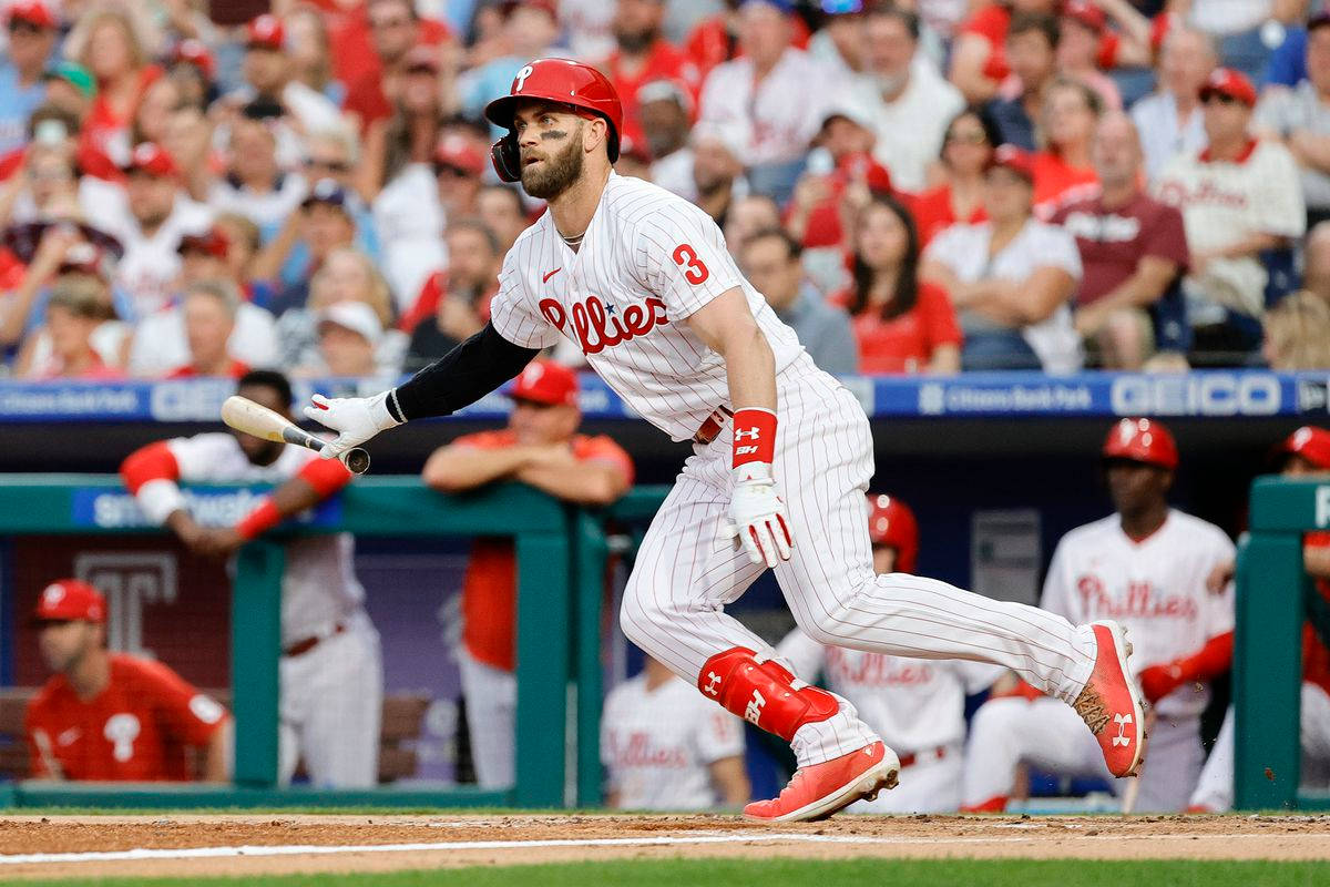 Phillies 桌布 壁紙 — 一名身穿紅白球衣的棒球選手在日間比賽中全神貫注地揮棒擊球。