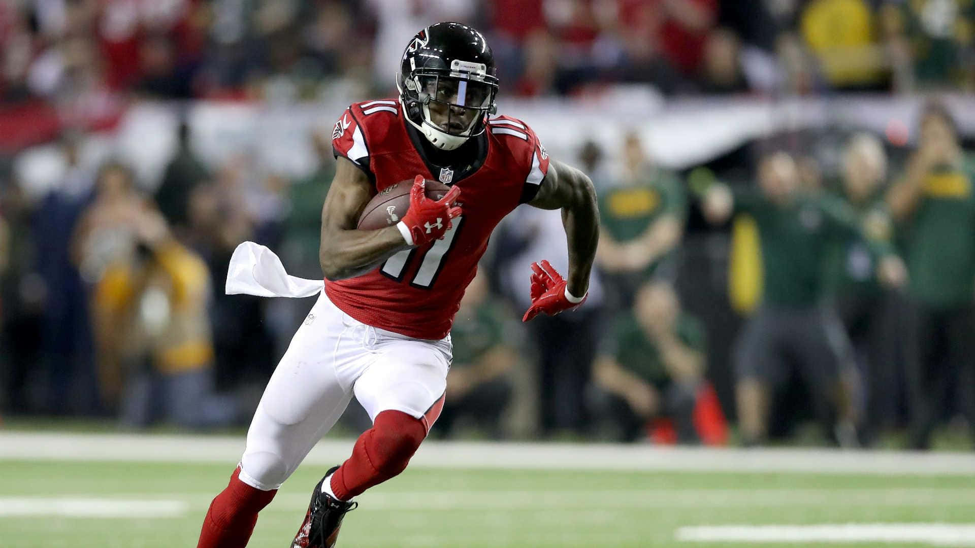 Julio Jones 桌布 壁紙 — 一名身穿紅白球衣的足球員在夜間比賽中，於球場燈光下帶球衝刺。