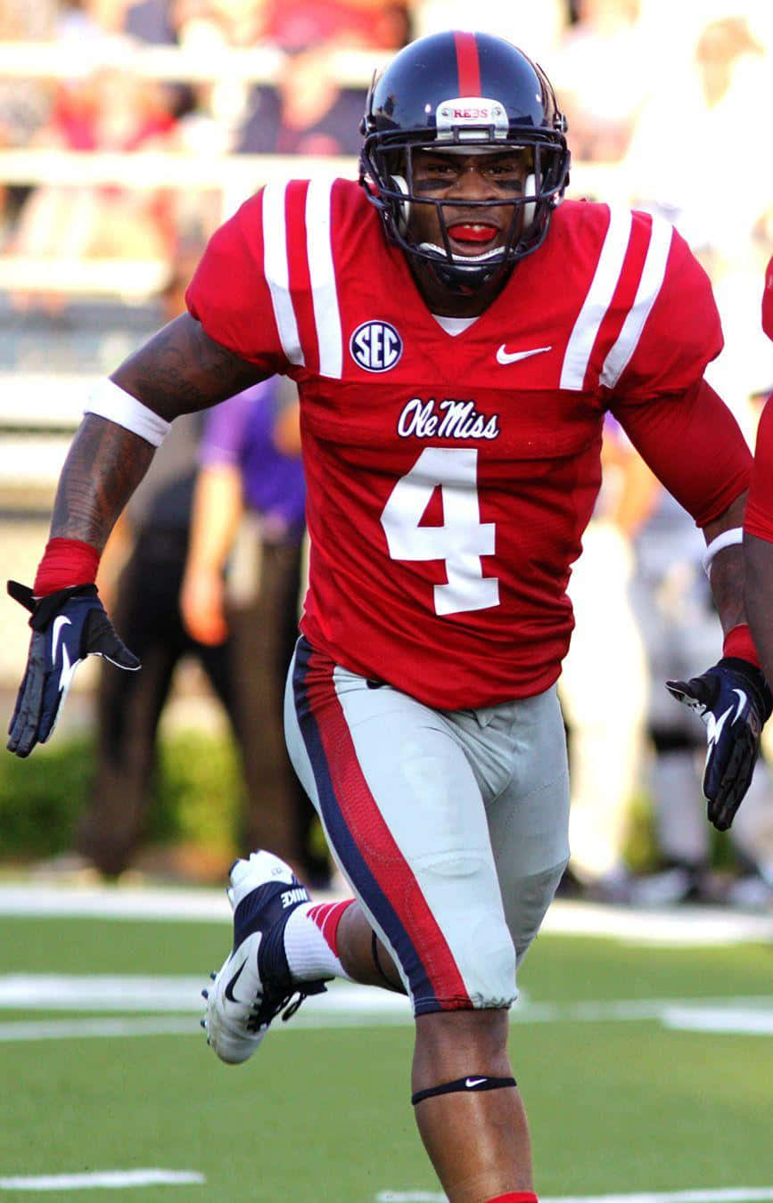 運動 桌布 壁紙 — 一名身穿紅色 Ole Miss 球衣、背號 4 的美式足球員在陽光明媚的球場上全力衝刺。