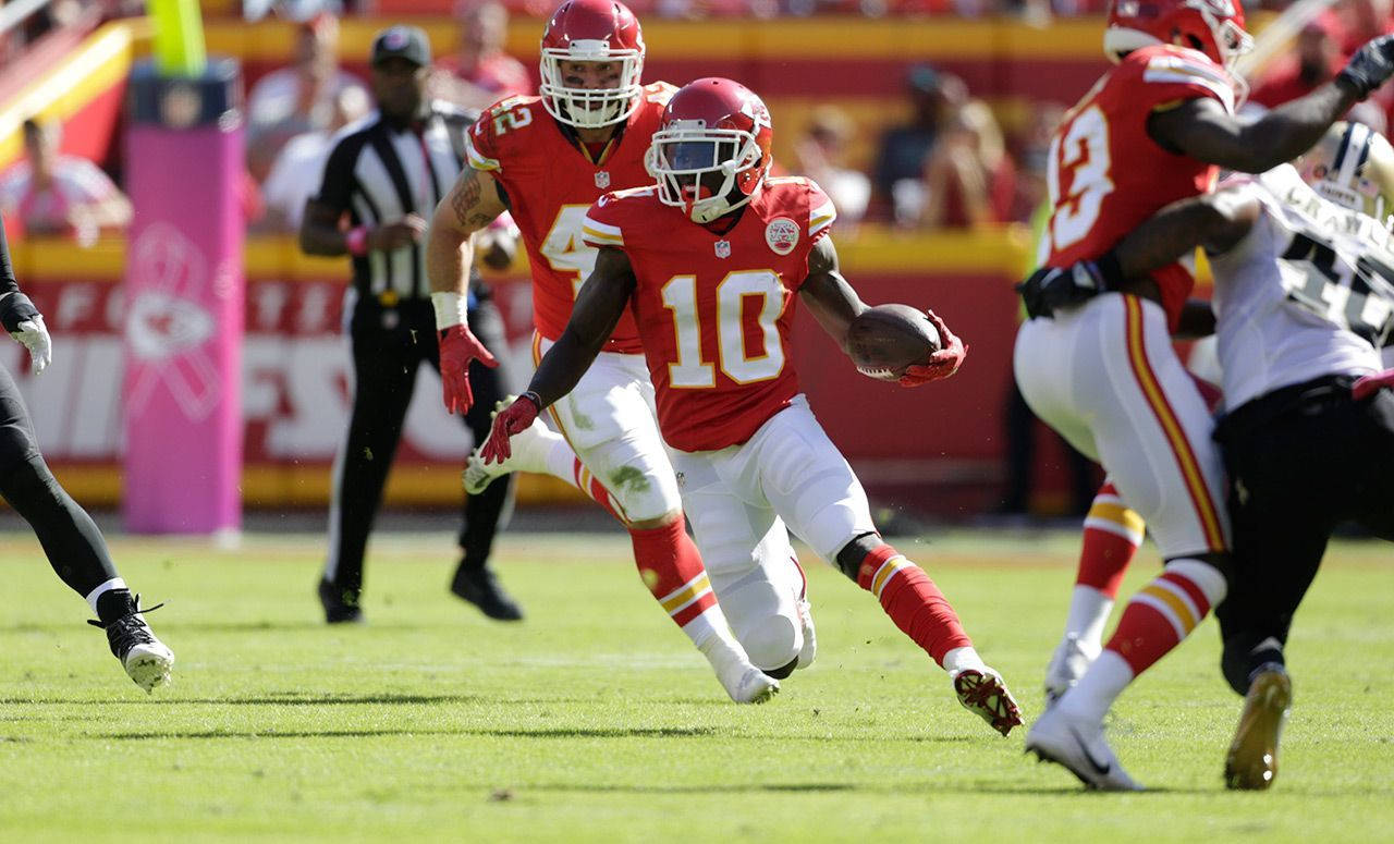 Tyreek Hill 桌布 壁紙 — 一名身穿紅色10號球衣的堪薩斯城酋長隊球員，在日間的NFL比賽中，於充滿活力的綠色球場上帶著橄欖球奔跑。