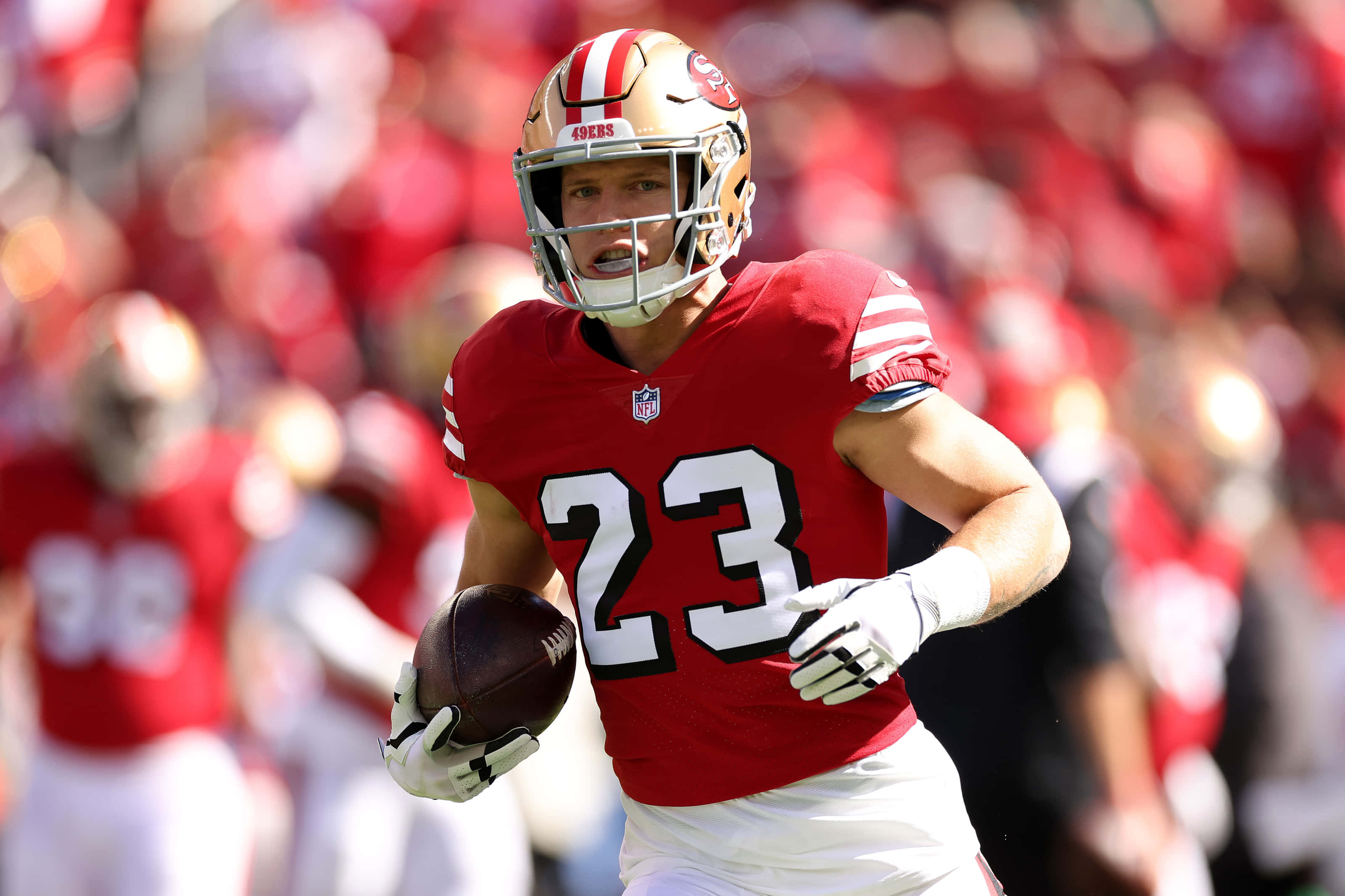 Christian Mccaffrey 桌布 壁紙 — 一名身穿紅色23號球衣的舊金山49人美式足球員在日間比賽中帶球衝刺。