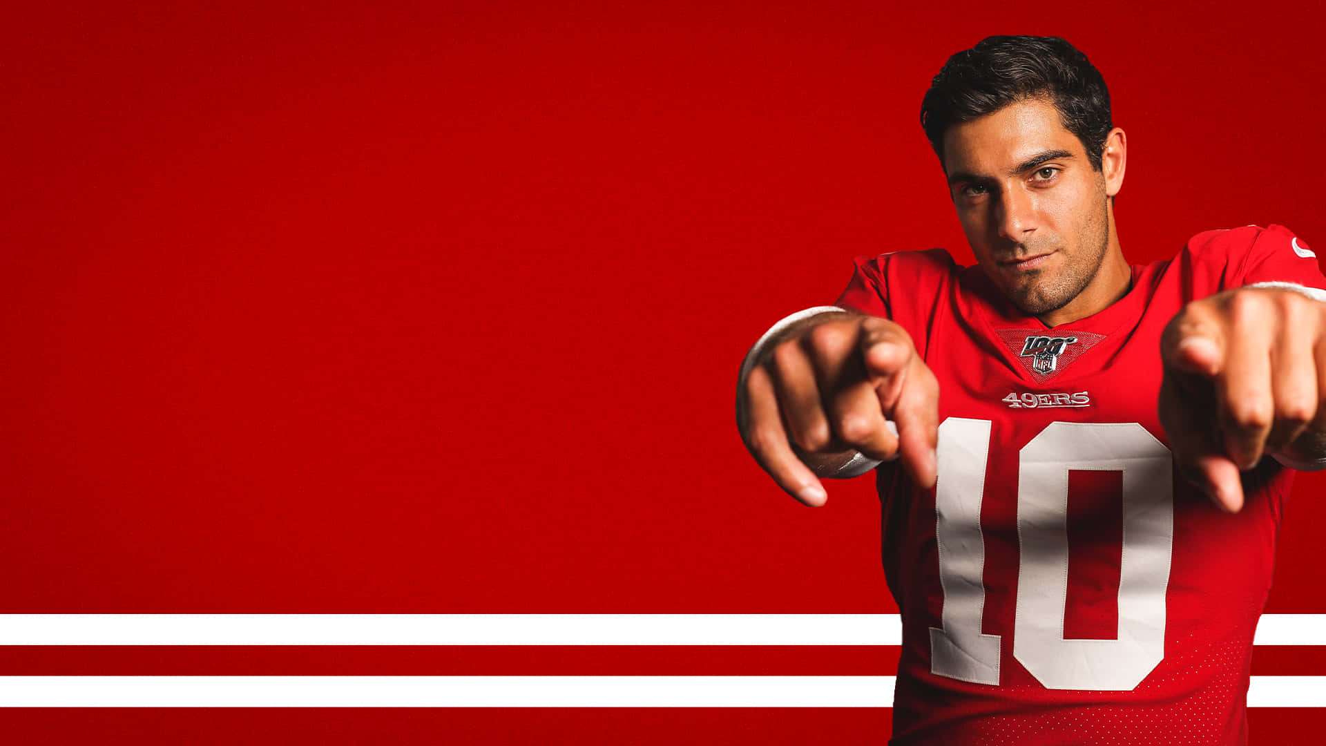 49ers 桌布 壁紙 — 一名身穿紅色49ers球衣、號碼10的美式足球員，在帶有白色條紋的醒目紅色背景前，直接指向觀眾。