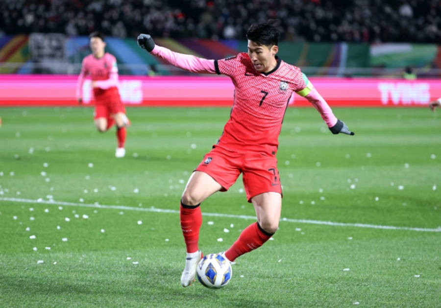 Football Players 桌布 壁紙 — 一名身穿紅色7號球衣的足球運動員在體育場燈光下，於綠色球場上控球，紙屑飄落。