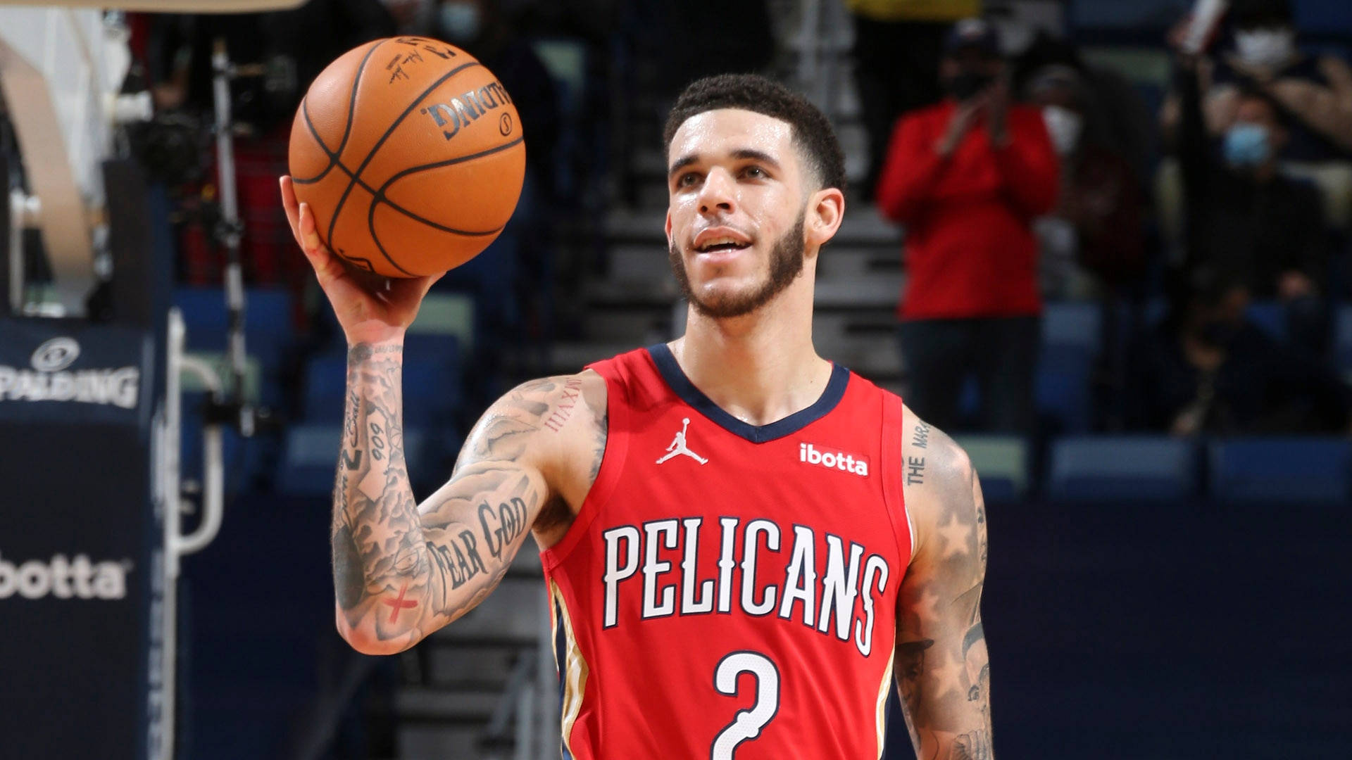 籃球 桌布 壁紙 — 一名身穿紅色Pelicans球衣的籃球運動員在比賽中持球，手臂上的刺青清晰可見。
